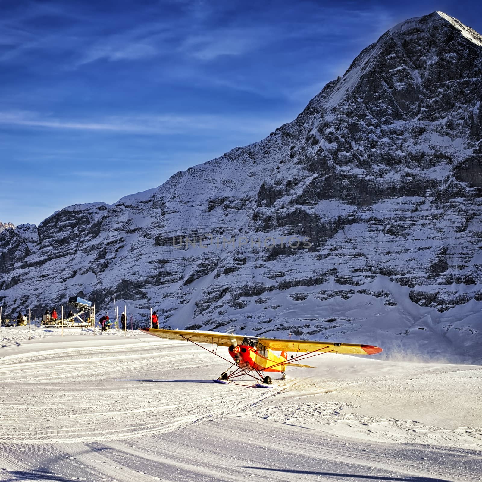 Yellow airplane landing to  alpine resort in swiss alps in winter