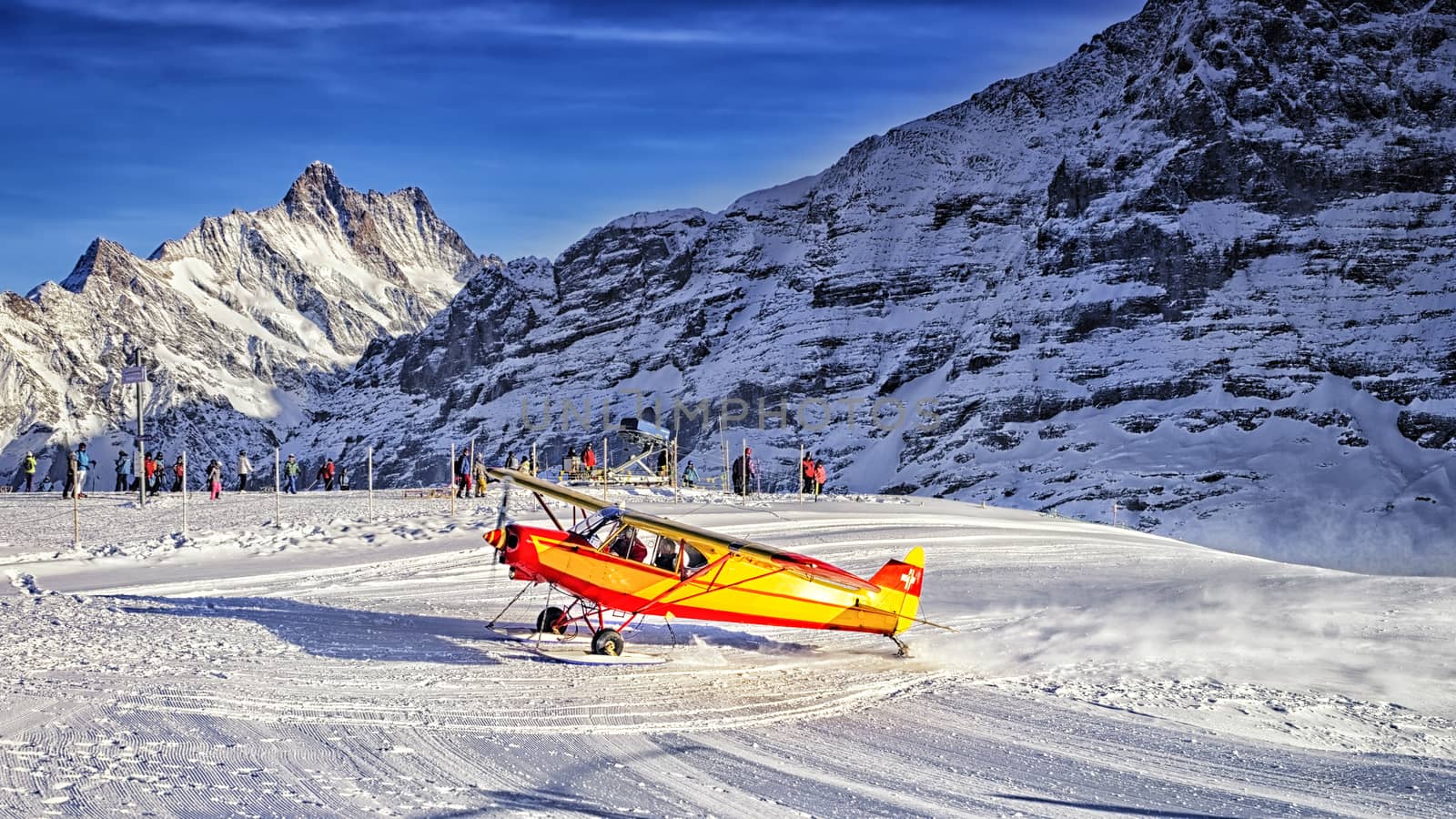 Yellow airplane landing to  alpine resort in swiss alps in winter