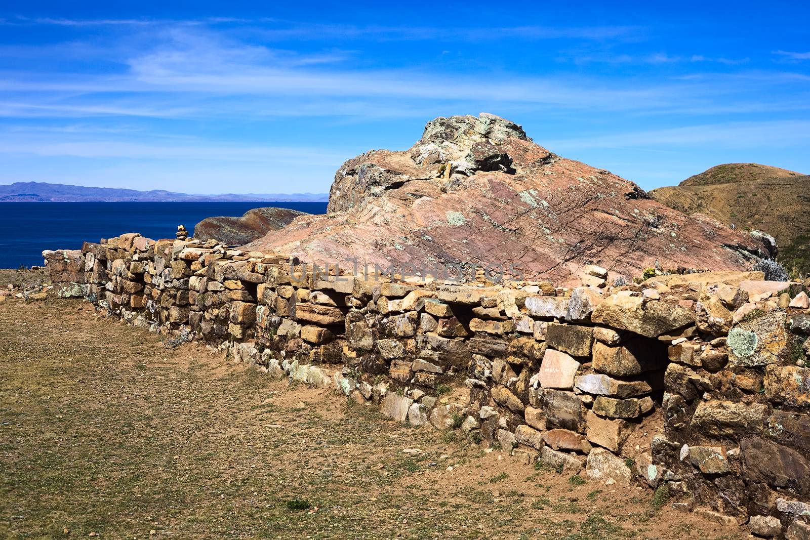 Low stone wall with many openings beside the Rock of the Puma, the sacred rock formation of the Tiwanaku and Inca cultures on the Isla del Sol (Island of the Sun) in Lake Titicaca, which is a popular travel destination in Bolivia