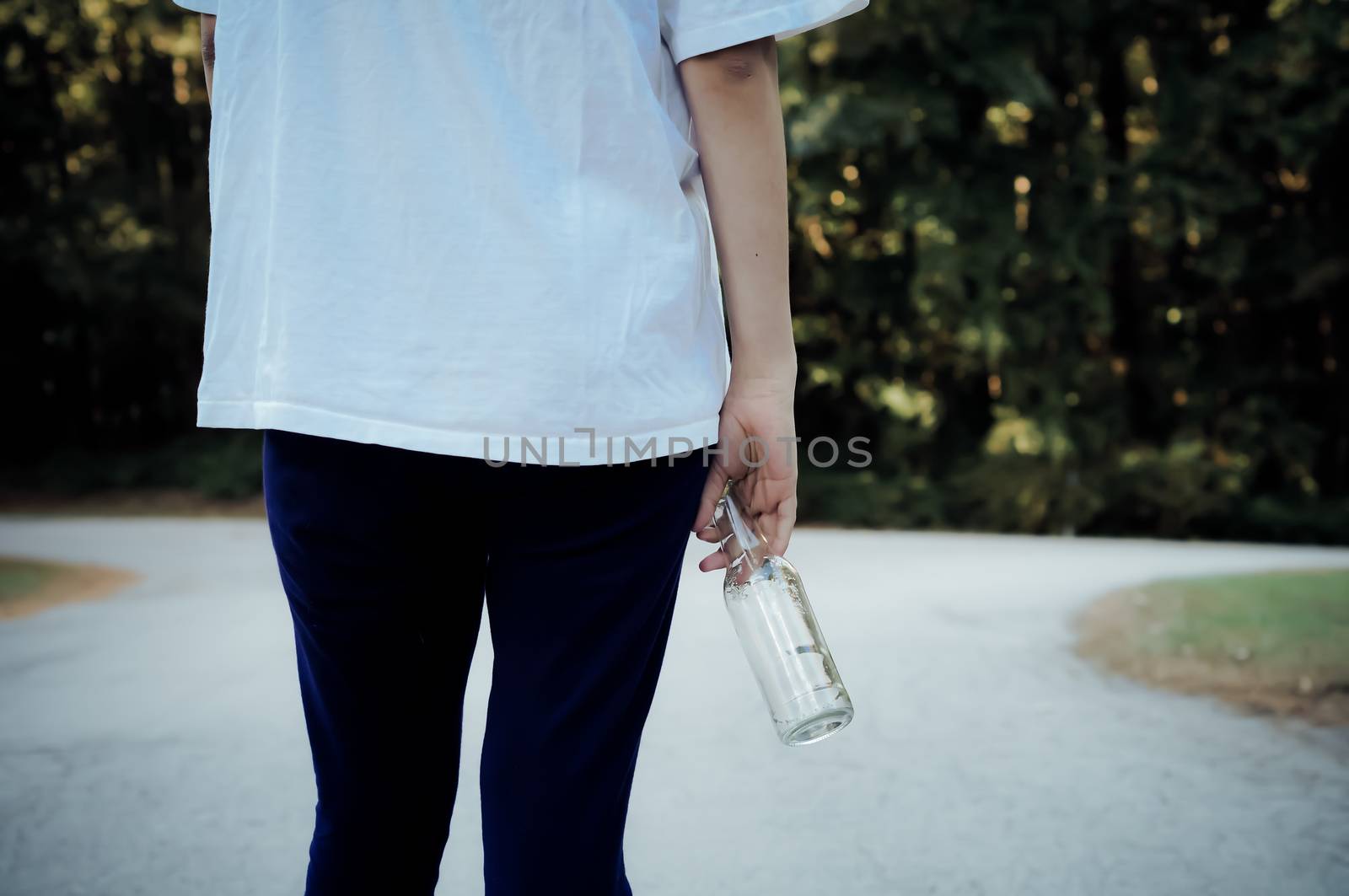 Teen girl standing at a fork in the road with a beer bottle