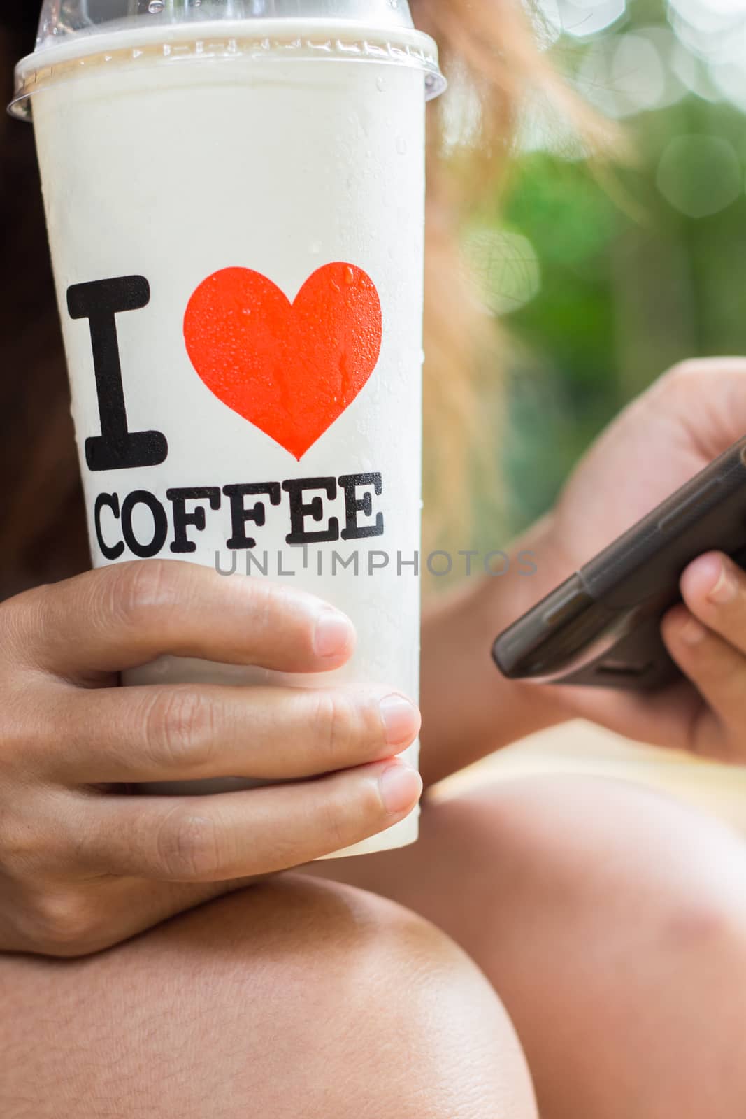 women hold ice coffee and use smart phone mobile by blackzheep