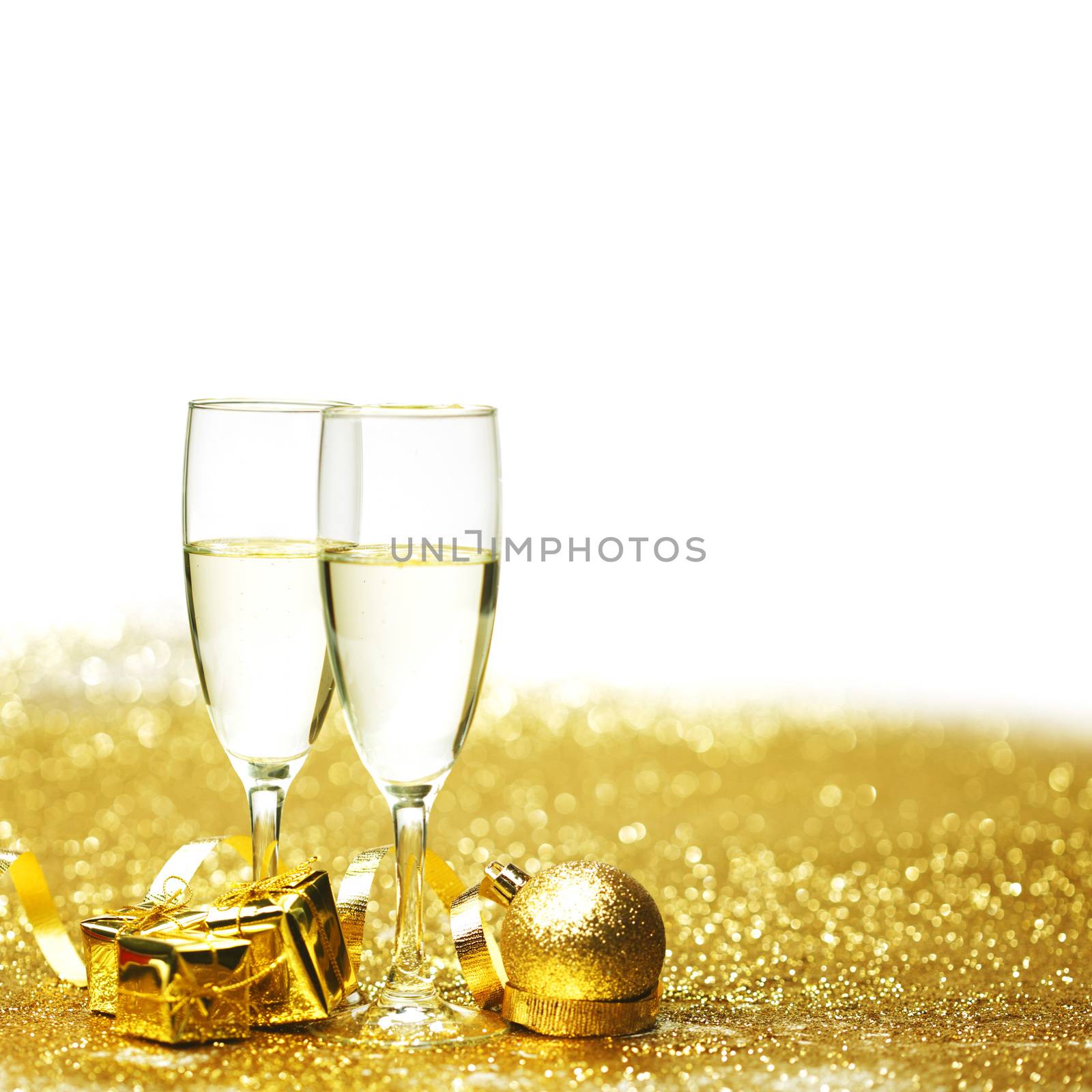 Champagne in glasses and gift box on golden background