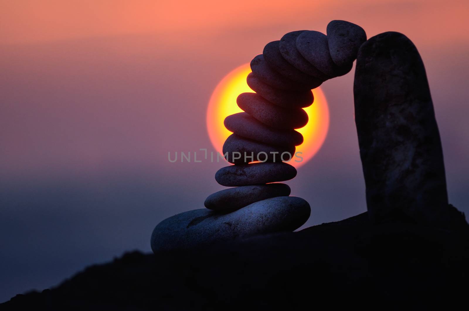 Balancing of pebbles on the boulder in the evening