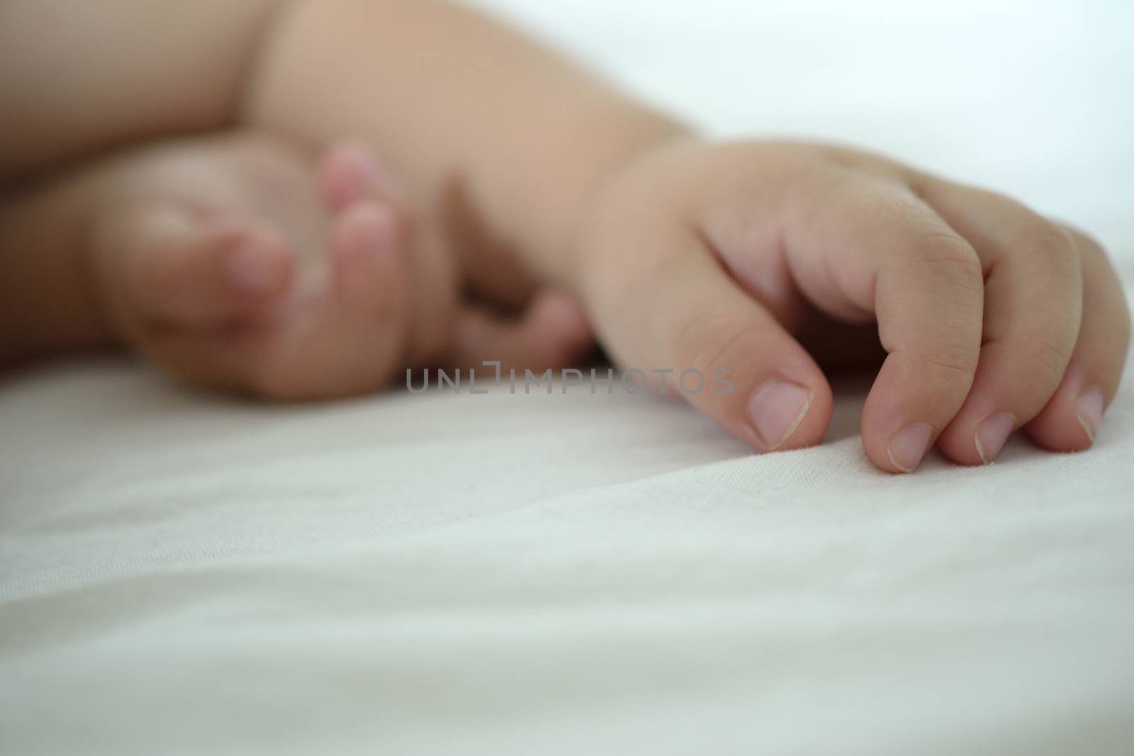 hands of a sleeping baby, white besheet and backround