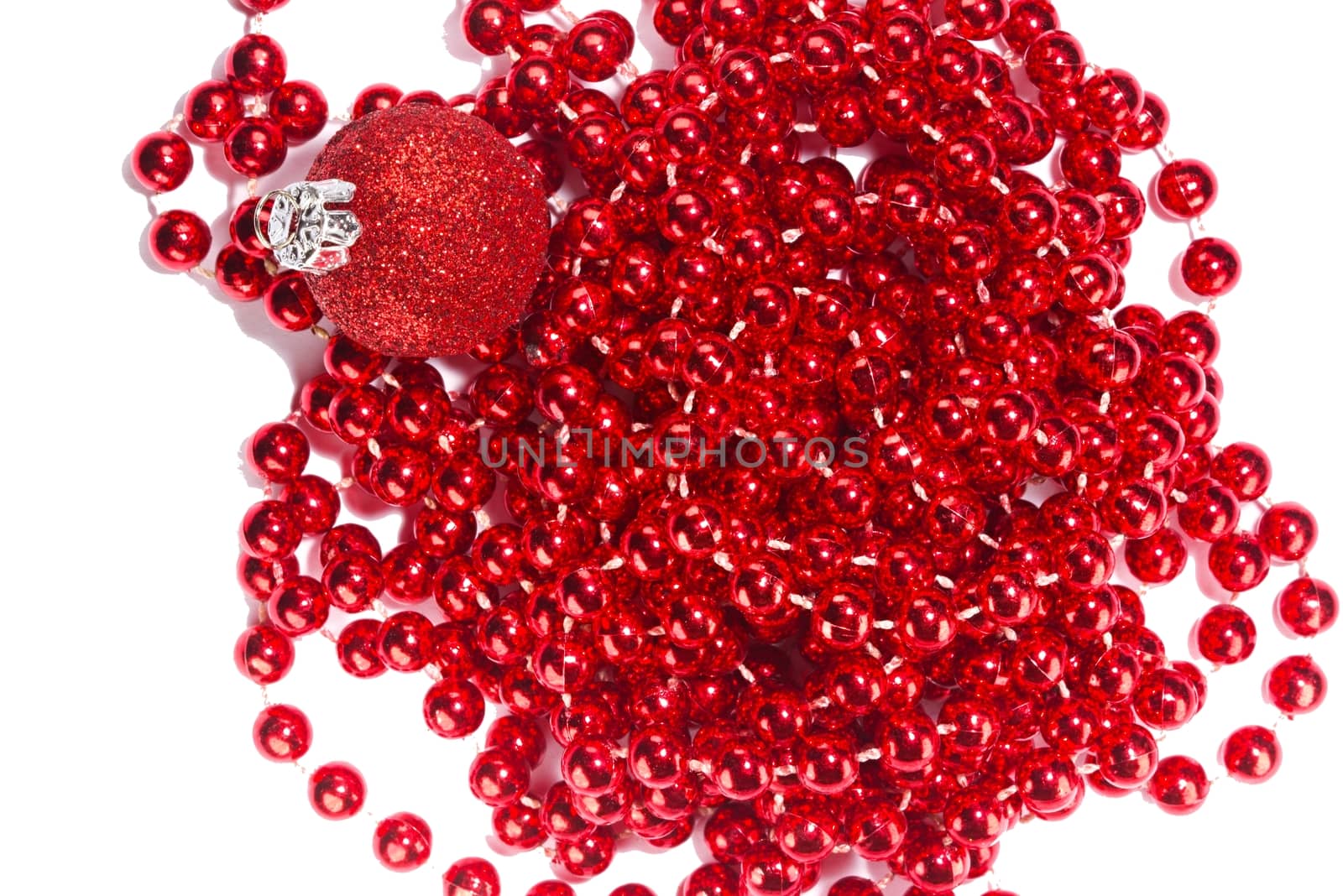 Photo shows a closeup of red Christmas beads and ornament on a white background.