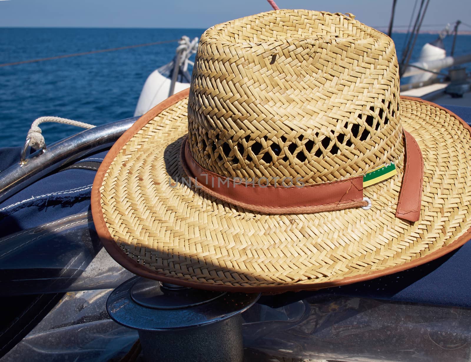 Straw hat on a sailing yacht with clear blue ocean background   