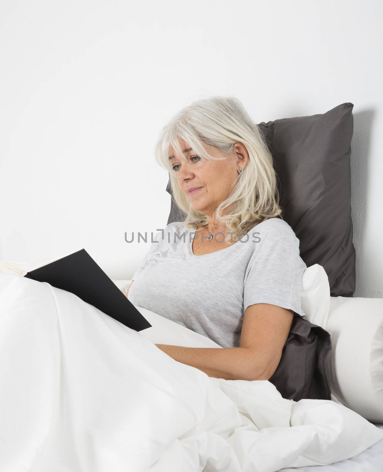 Woman reading a book in bed by gemenacom
