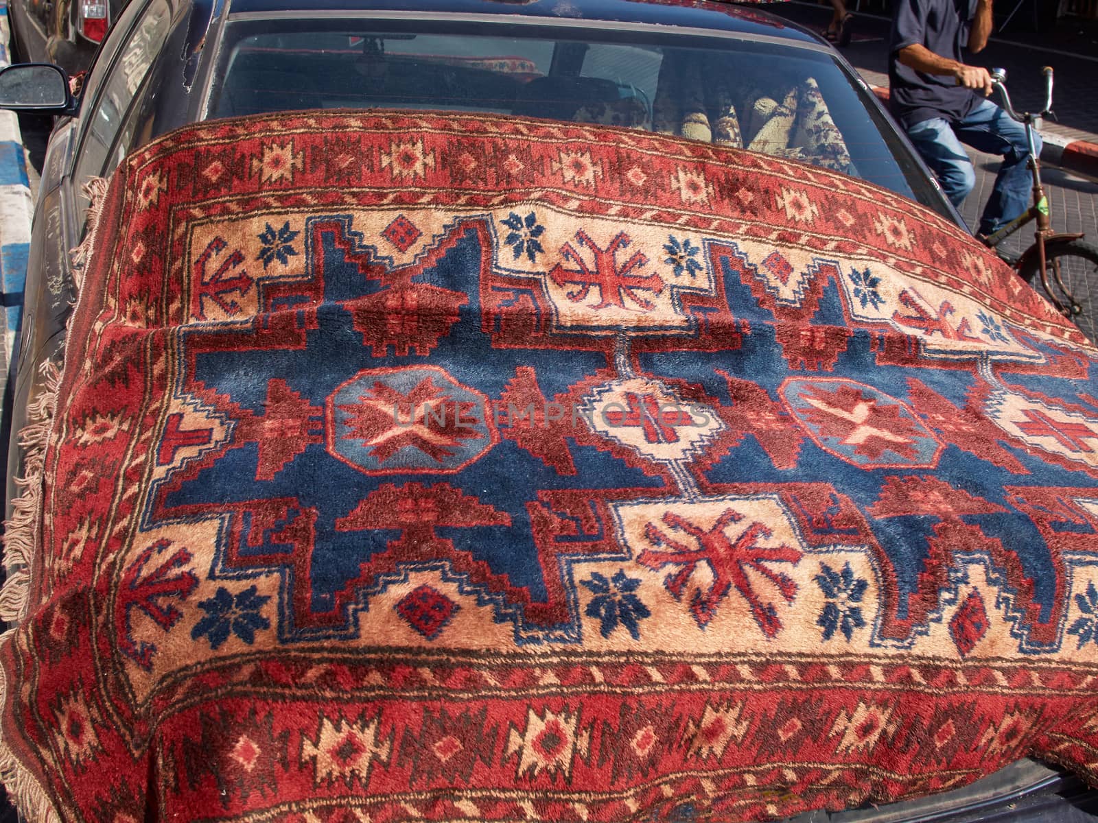 Oriental carpets in a flea market for display on a car 