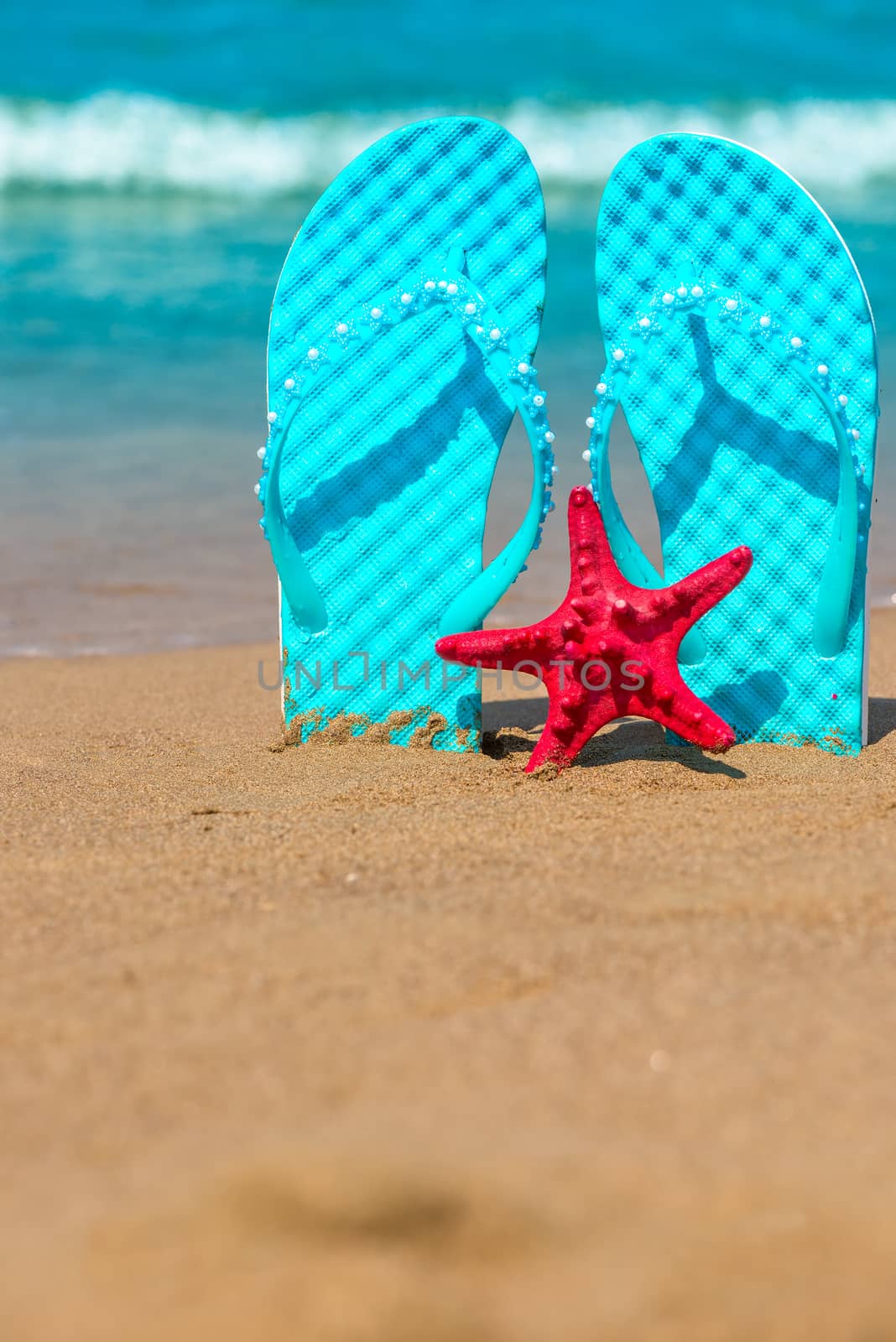 Vertical shot of beach shoes and starfish on the sea