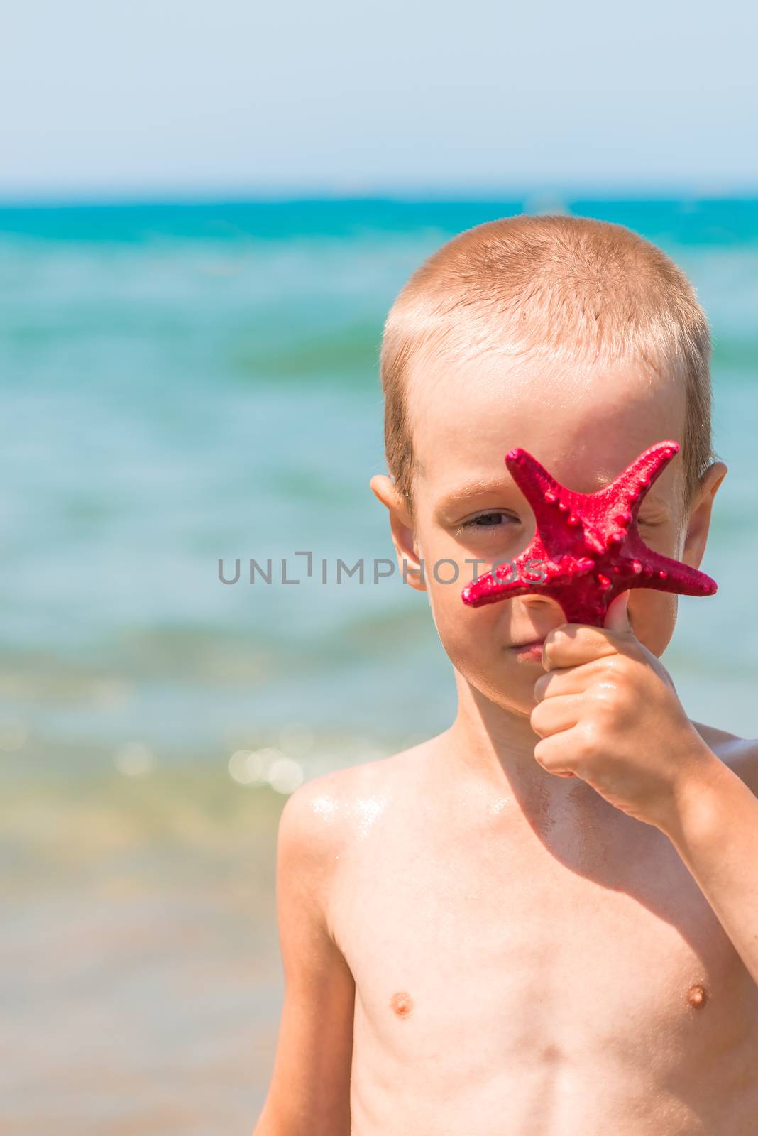 vertical portrait of a boy with a red star on the beach