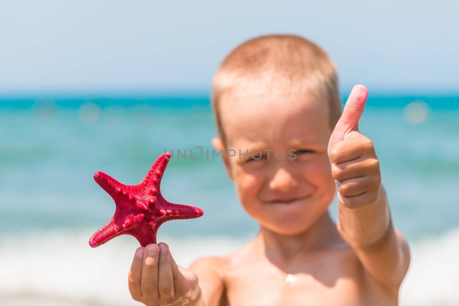 cheerful and happy boy with starfish on the beach