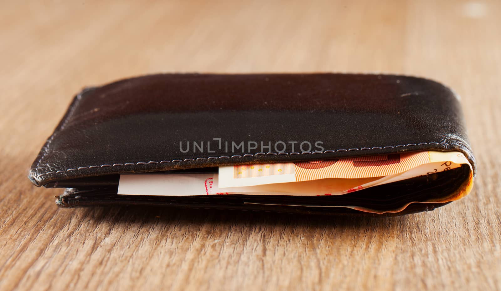 Full black wallet over a wooden table