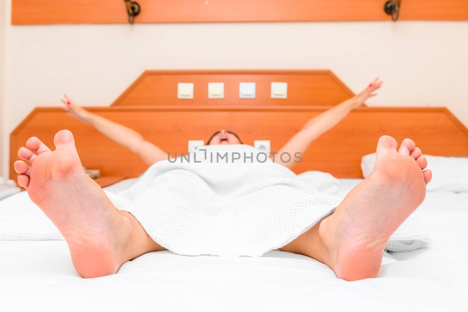 young girl lying in bed yawning and stretching