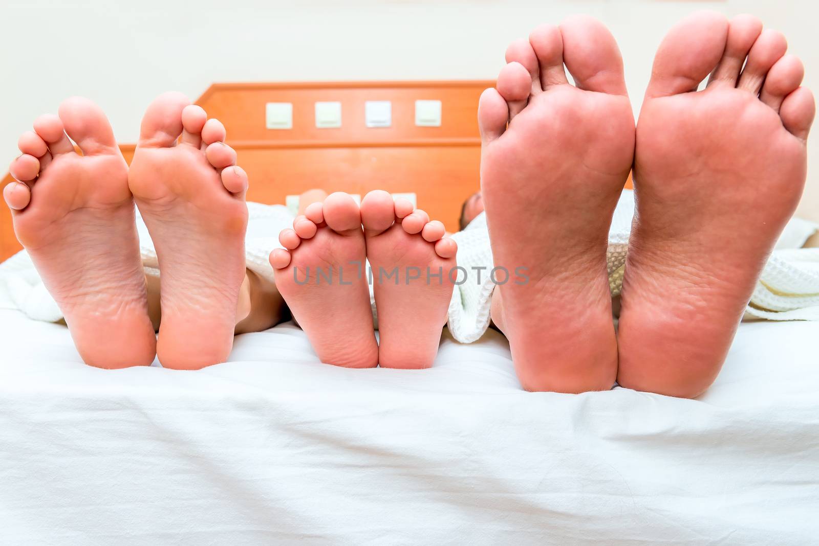 family of three people sleeping in one bed, feet close-up by kosmsos111