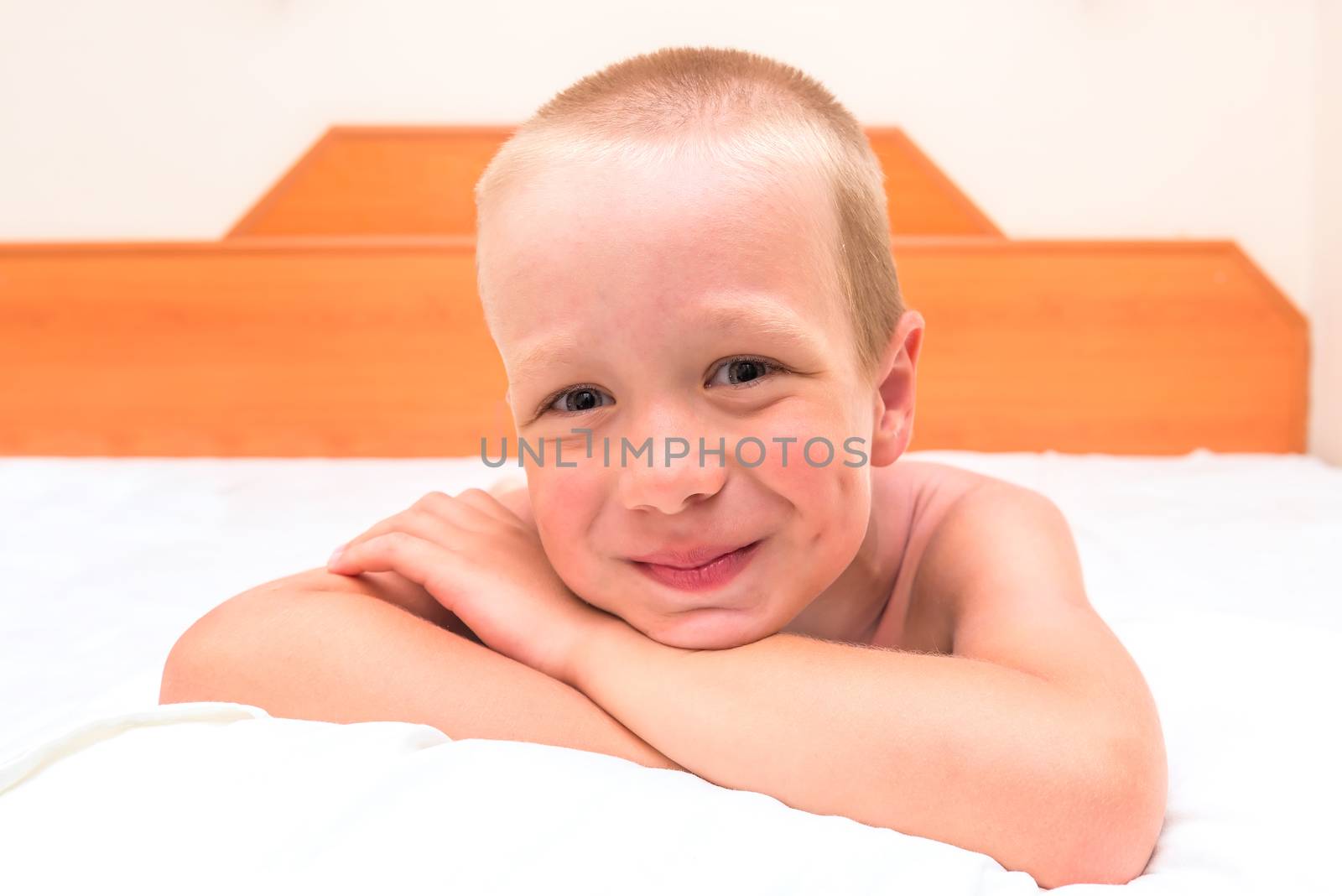 mischievous preschooler resting in bed and smiling