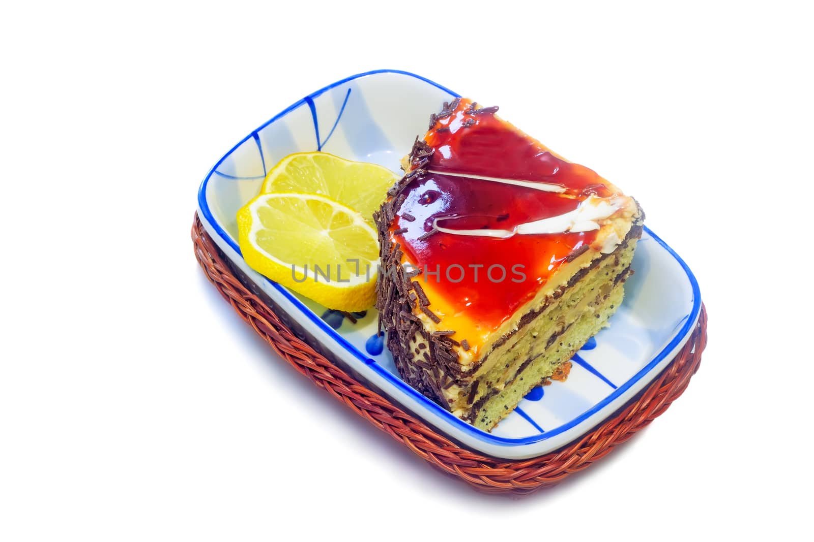 In a beautiful ceramic vase is the dessert: a delicious cake and two slices of lemon. Presented on a white background.