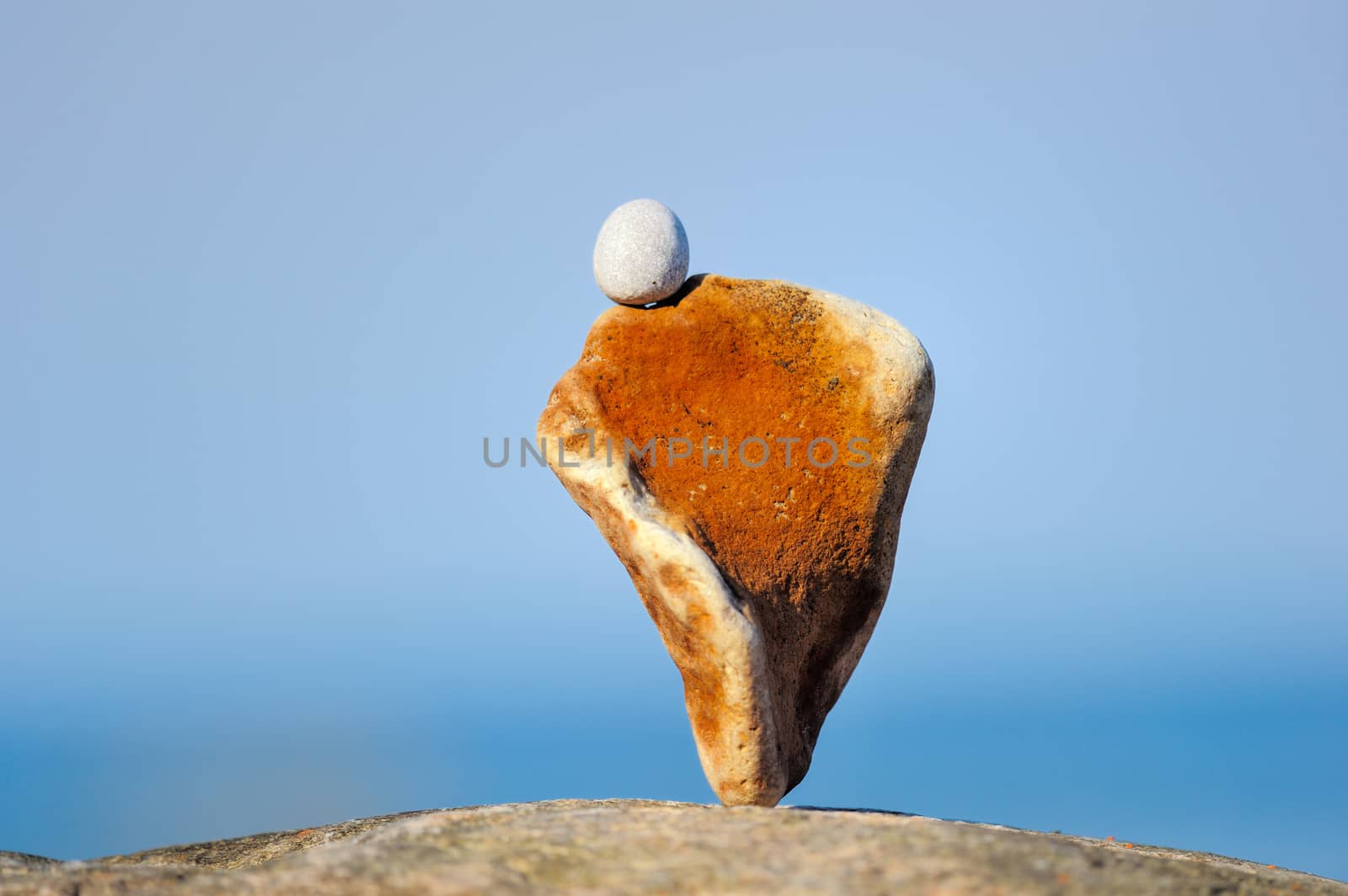 Balancing of red and white stones on the seacoast