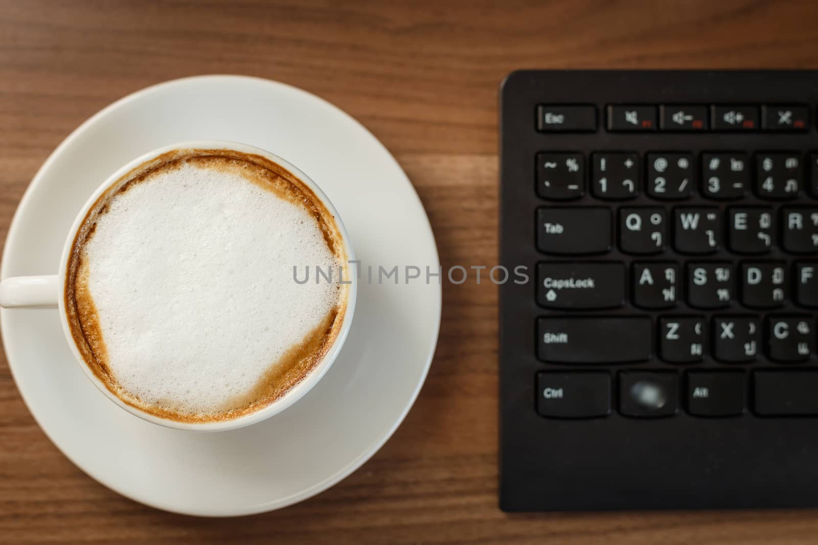 Coffee cup and computer on table by nanDphanuwat