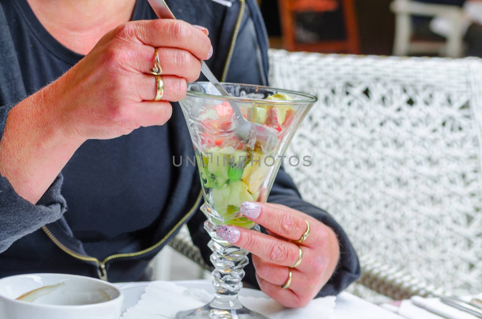 Woman sitting in a restaurant and eats an exotic fruit salad. 