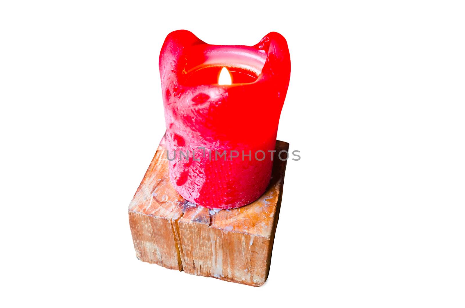 A single burning red candle on a table. Standing on a wooden candle stand. On a white background