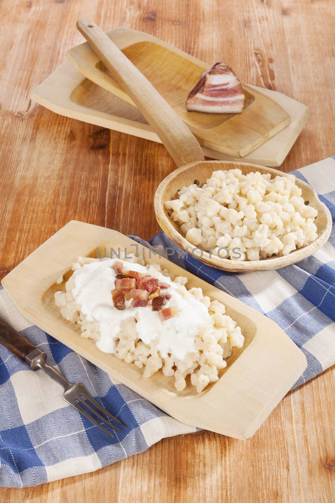 Bryndzove halusky. Potato dumplings with bryndza sheep cheese and bacon on wooden background. Bryndzove halusky, traditional national slovak food, country style.