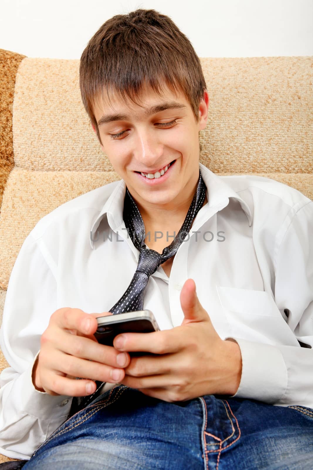 Tired and Satisfied Teenager with Cellphone on the Sofa at the Home