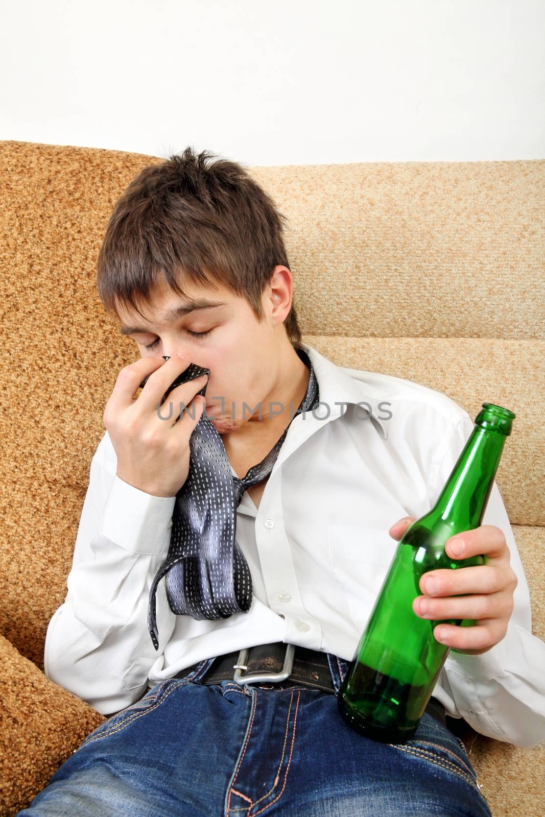 Drunken Teenager with Bottle of the Beer on the Sofa at the Home