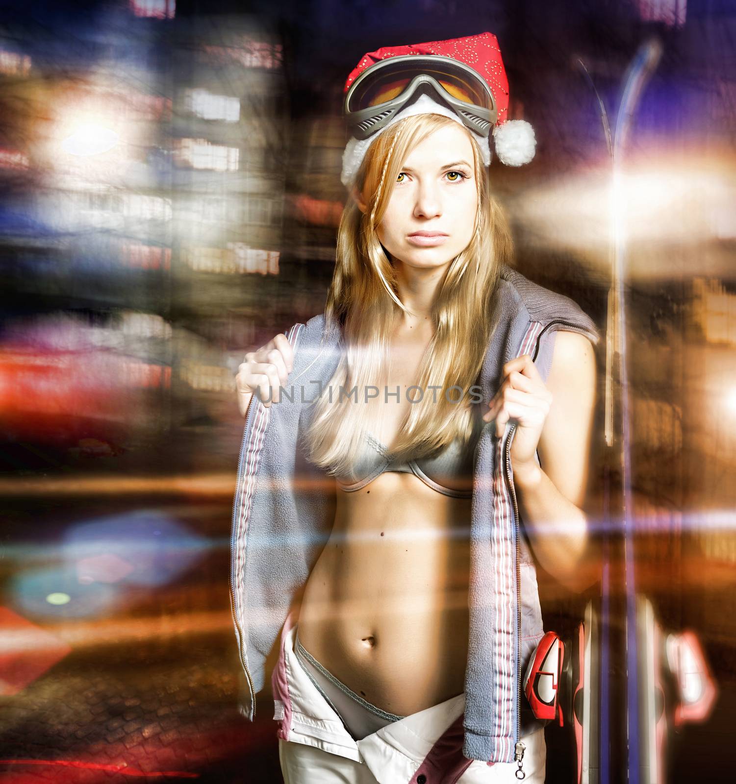 Young sexy woman with skis and in the lights of the night city