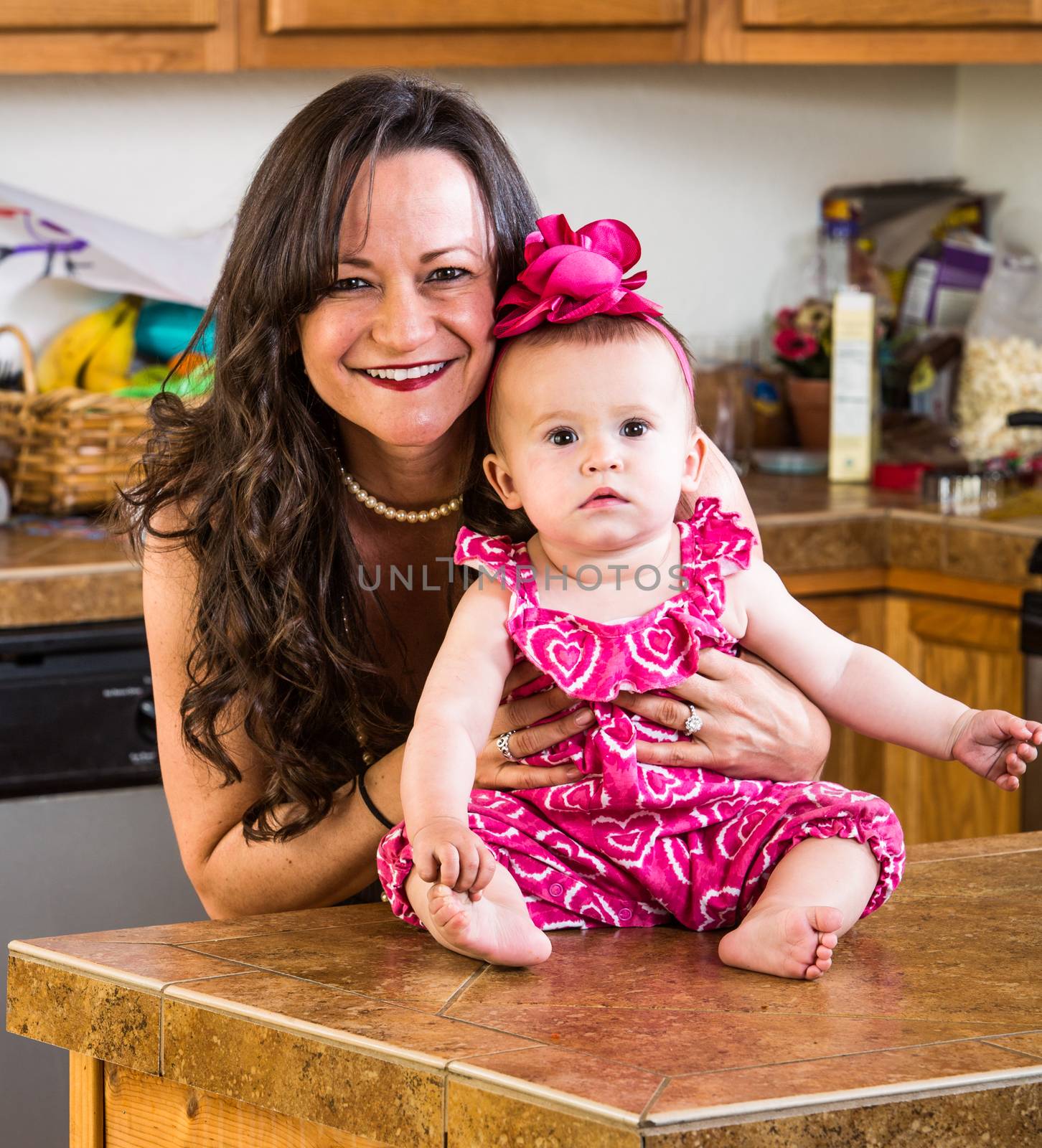 A mother in the kitchen poses with her baby