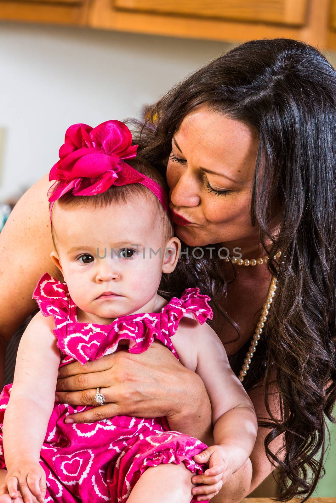 Woman in kitchen kisses her baby