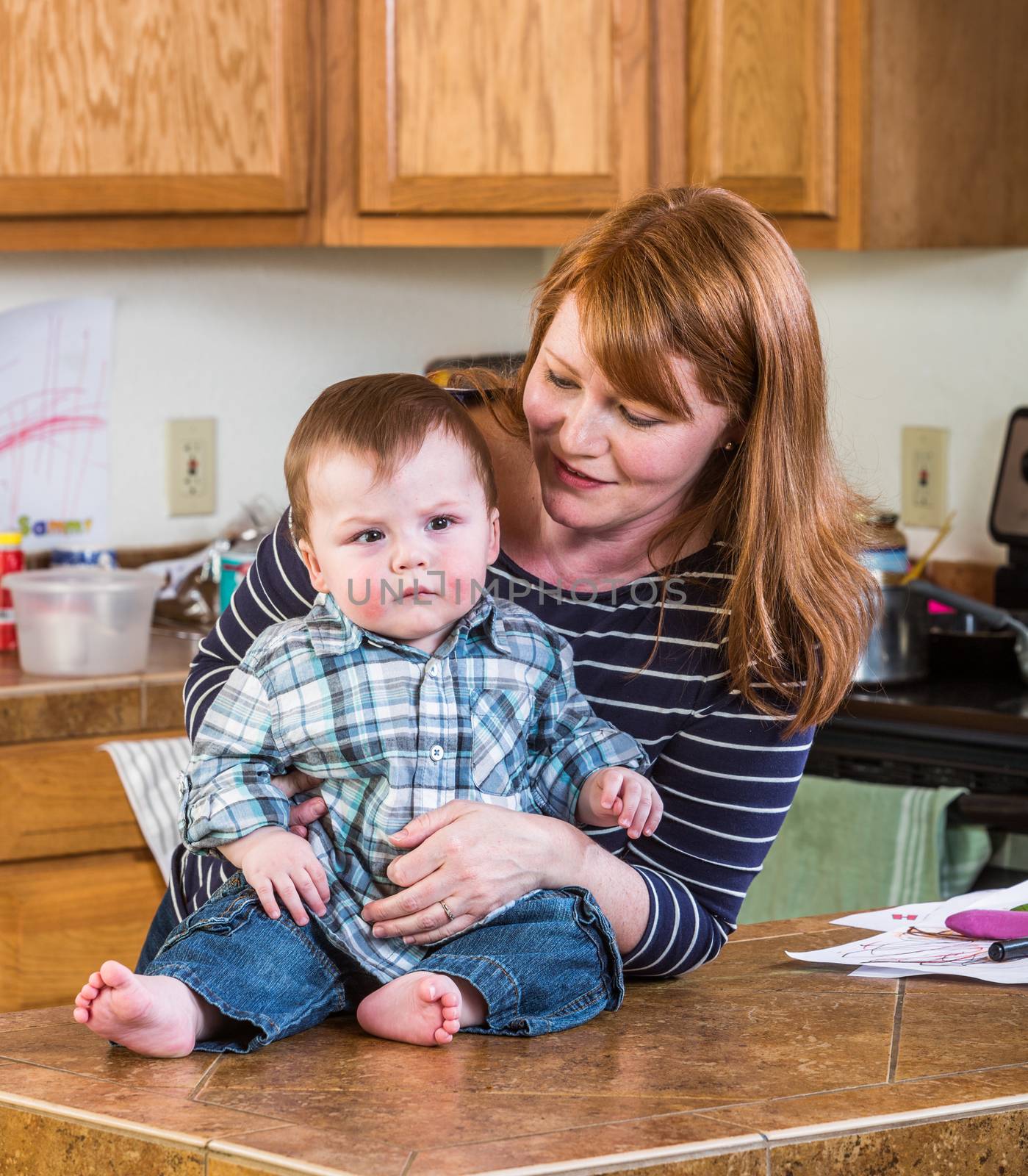 A woman in the kitchen poses with her baby
