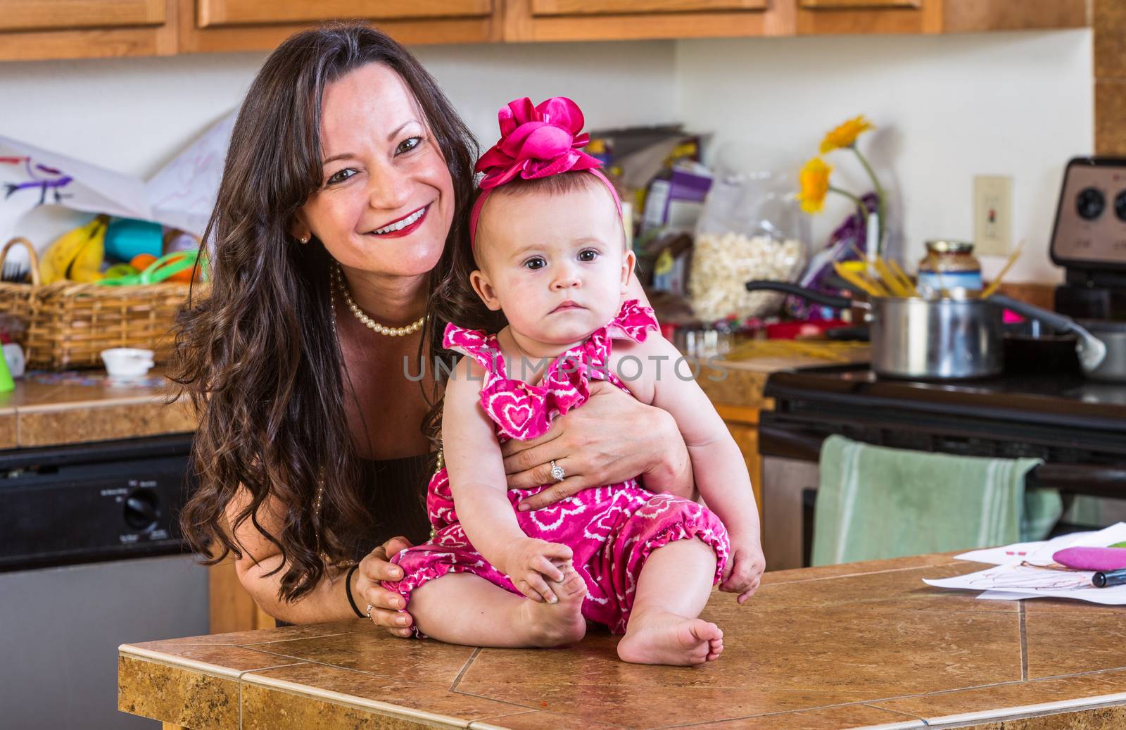 Smiling woman holds her baby in the kitchen