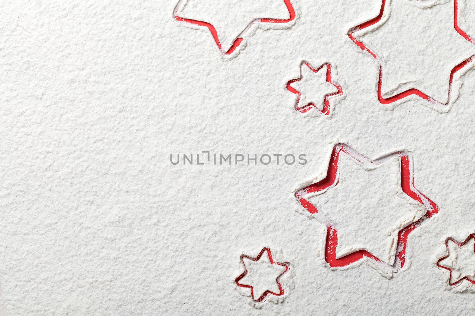 Christmas stars on flour background. White flour looks like snow. Top view