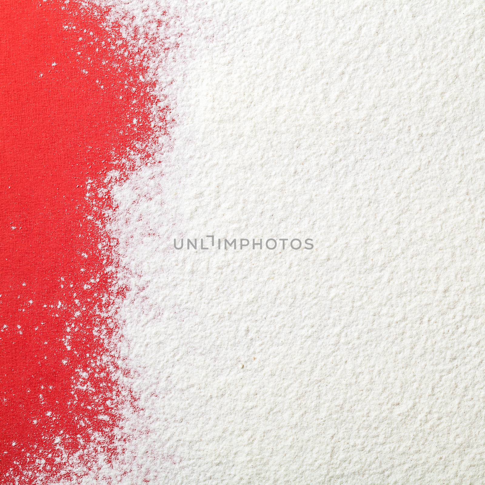 White wheat flour looks like snow on red paper background. Top view. Copy space