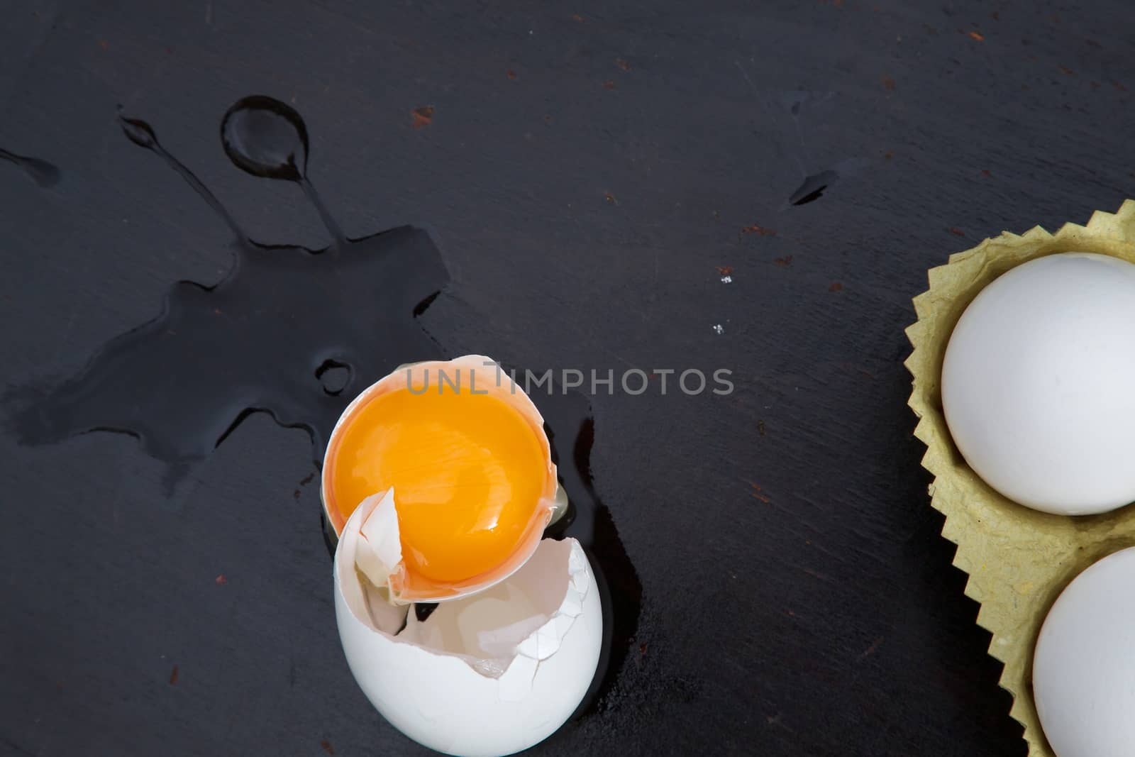 A broken egg on a black wooden surface