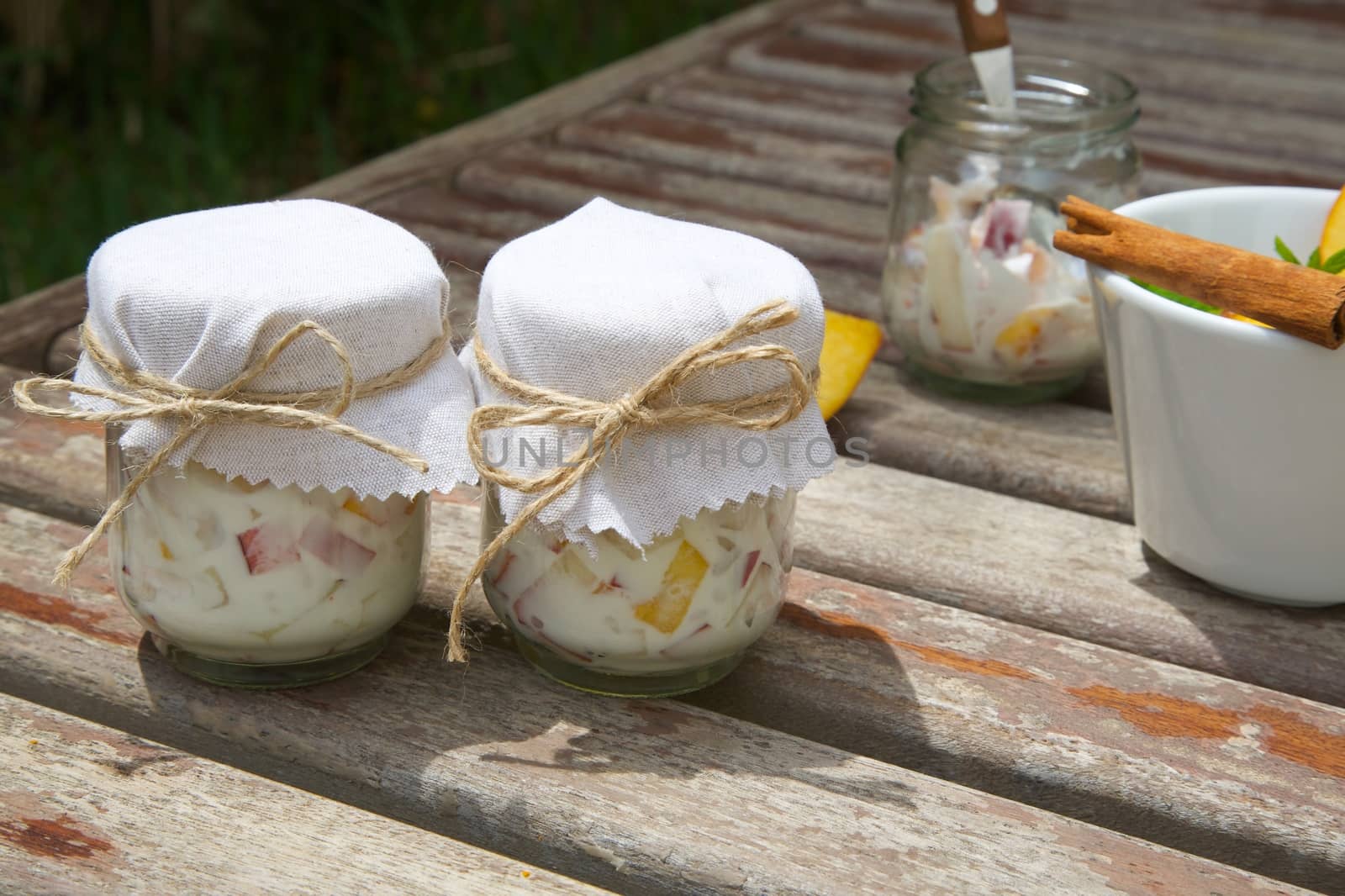 Two glasses of homemade yogurt with pieces of peach on an old wooden surface