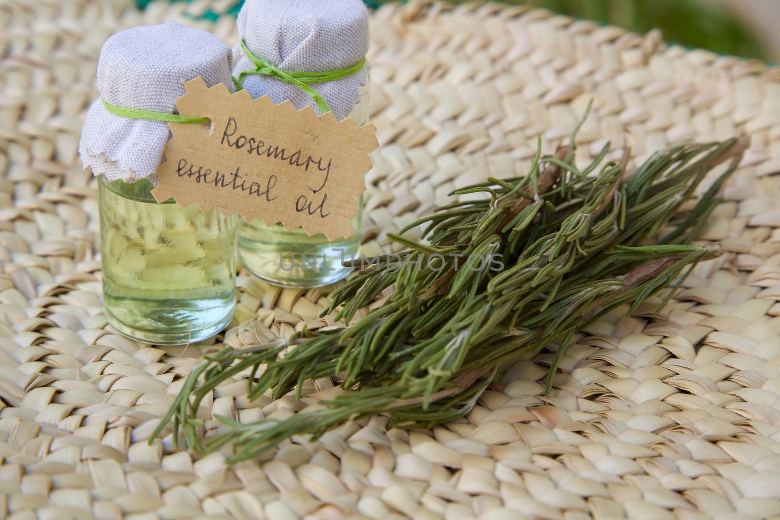Rosemary essential oil and rosemary branchlets in the background