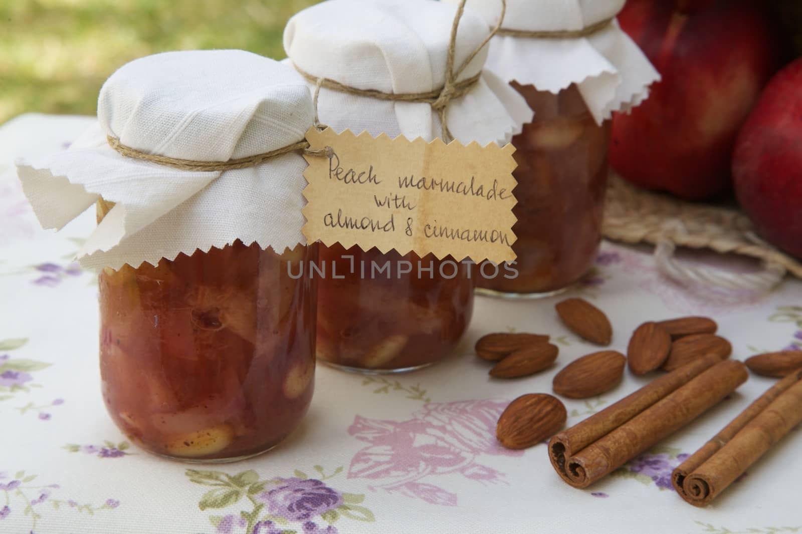 Homemade peach marmalade with almond nuts and cinnamon. Almonds,cinnamon sticks and fresh peaches in the background