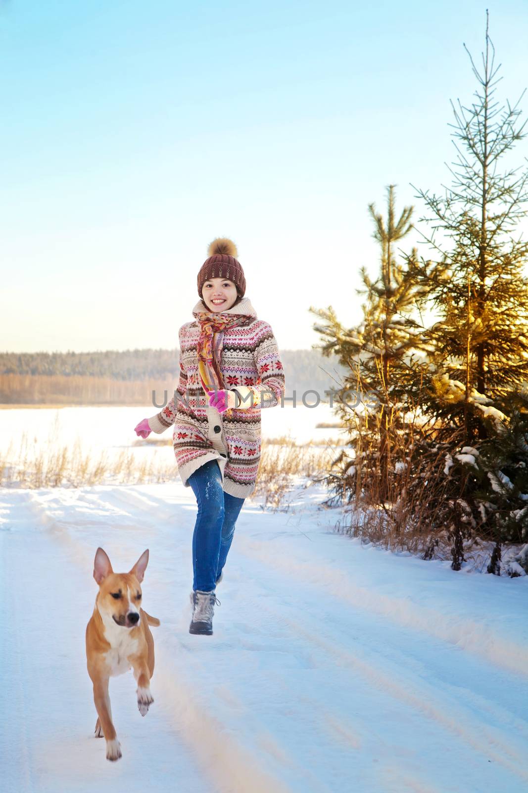 Portrait of the beautiful girl running near a dog in the winter wood