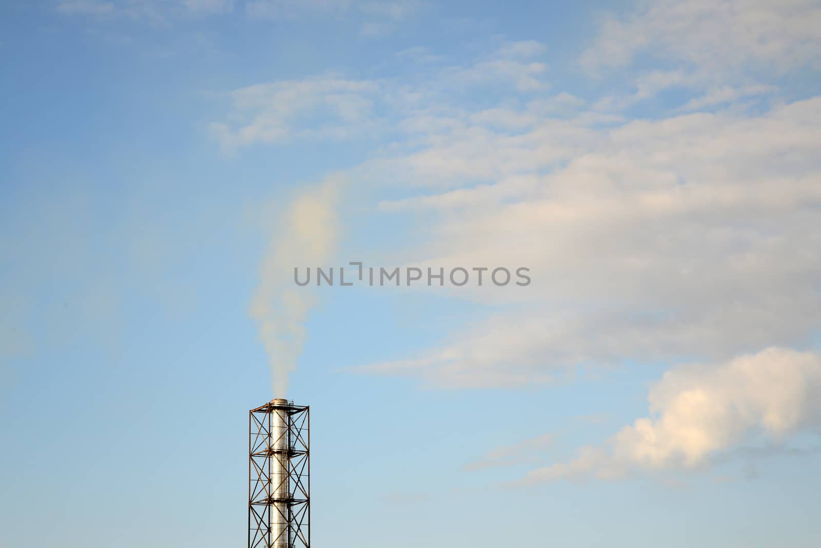 Photo of industrial smoke from a chimney on a blue sky. Illustration of industrial pollution, environmental problems.
Taken in Riga, Latvia.