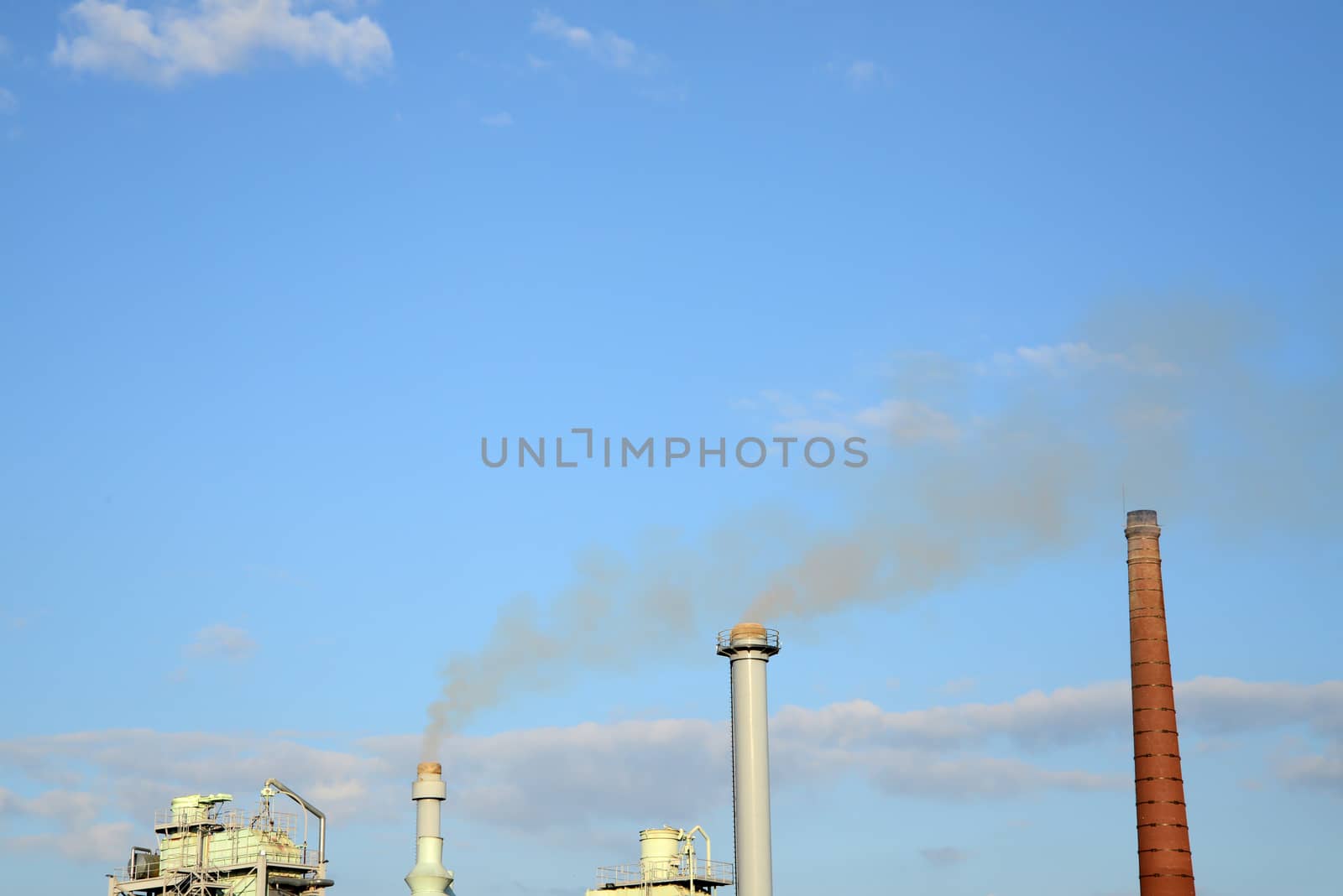 Photo of industrial smoke from chimneys on a blue sky. Illustration of industrial pollution, environmental problems.
Taken in Riga, Latvia.