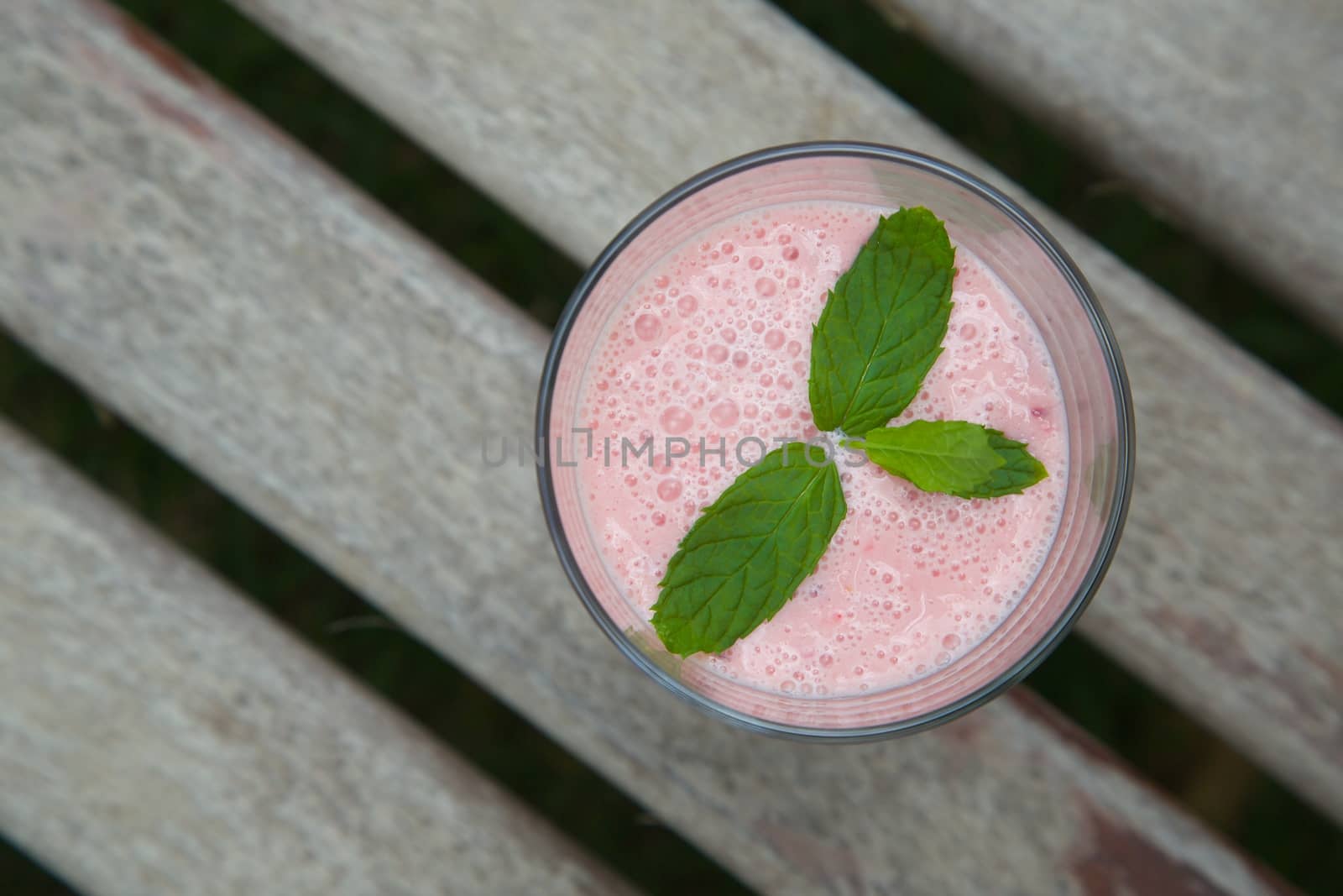 A glass of red berries smoothie with fresh peppermint leaves. Top view