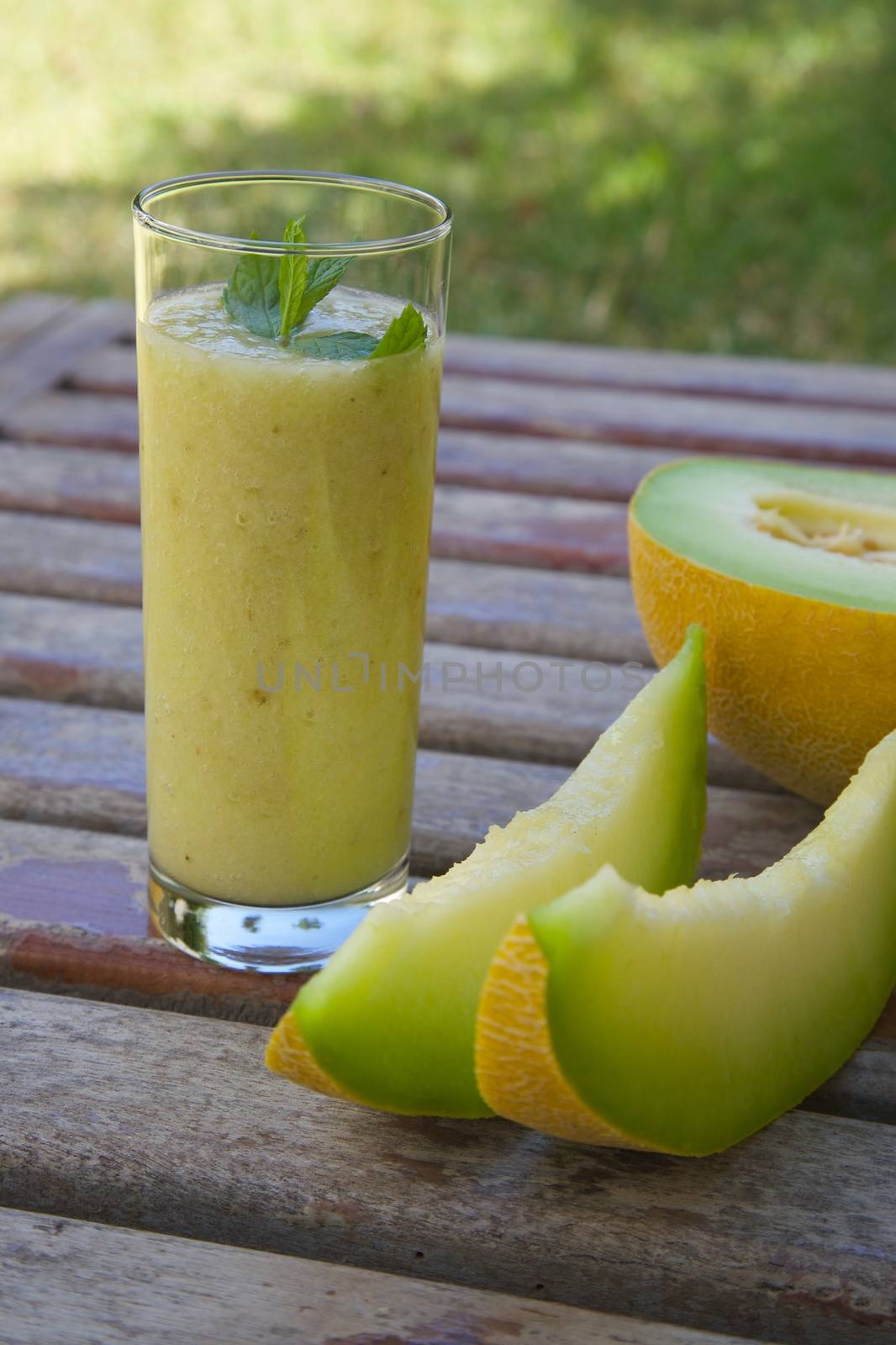 A glass of  green melon smoothie on an old wooden surface
