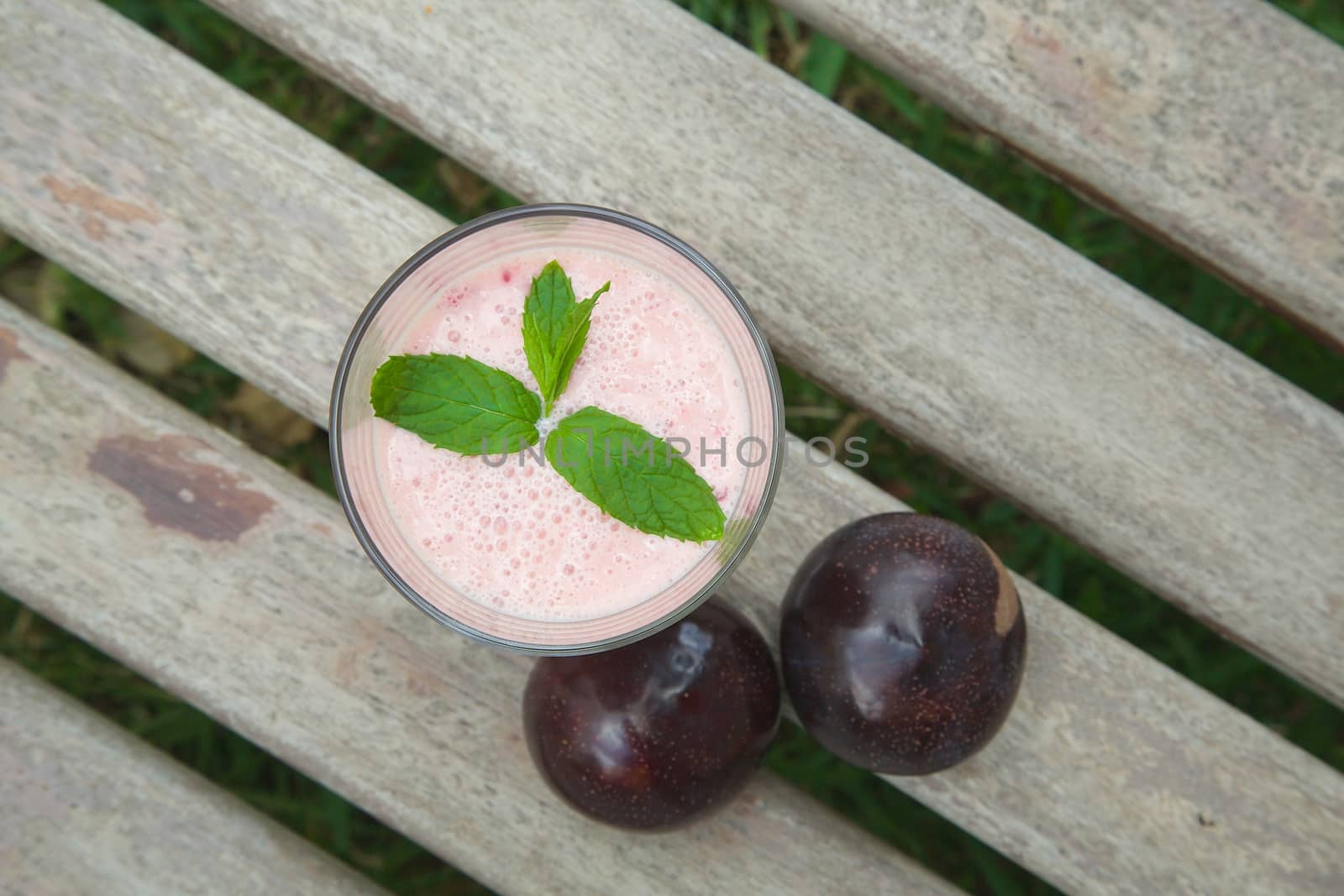 A glass of plum yogurt with fresh peppermint leaves. Top view
