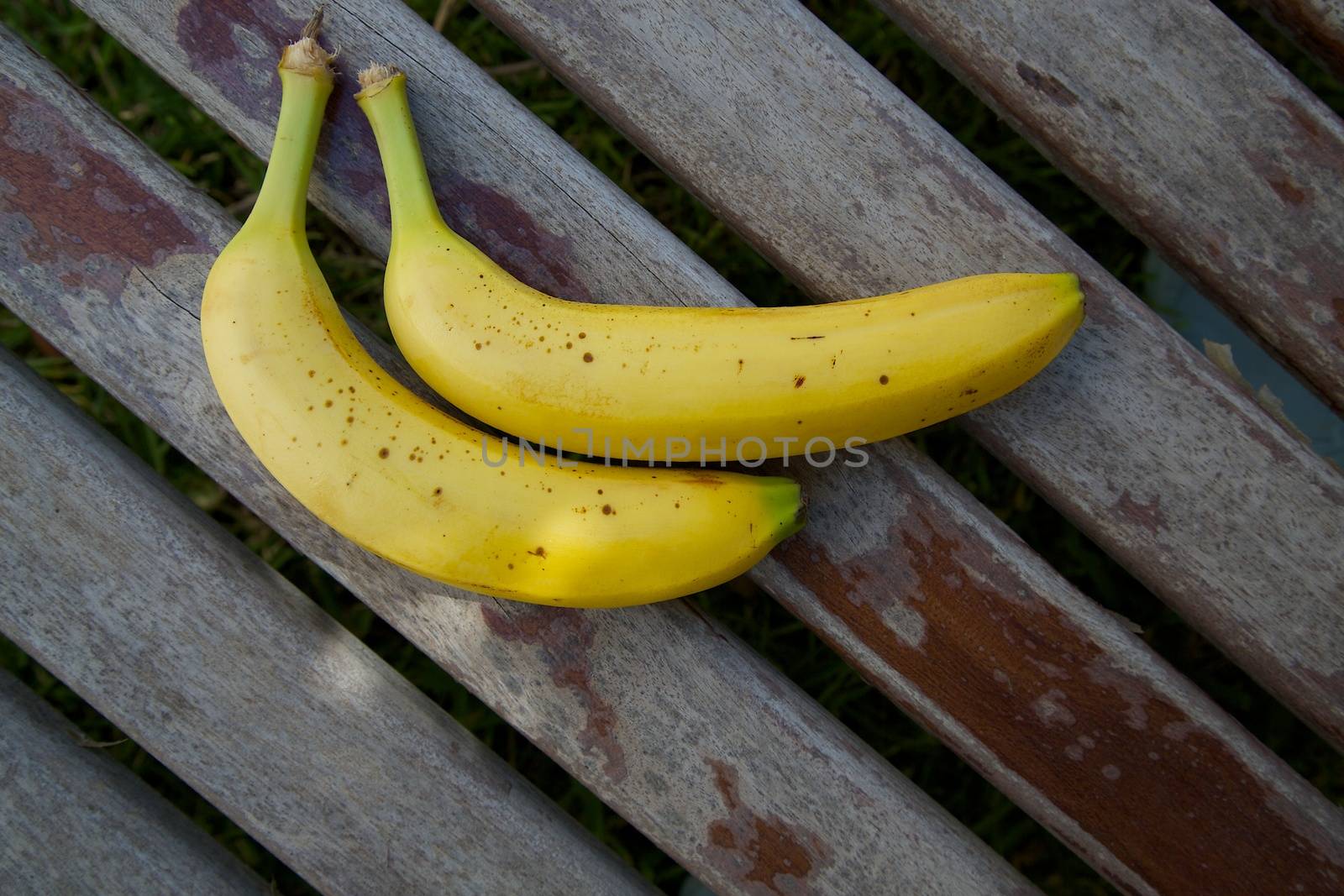 Two bananas on an old wooden surface by tolikoff_photography