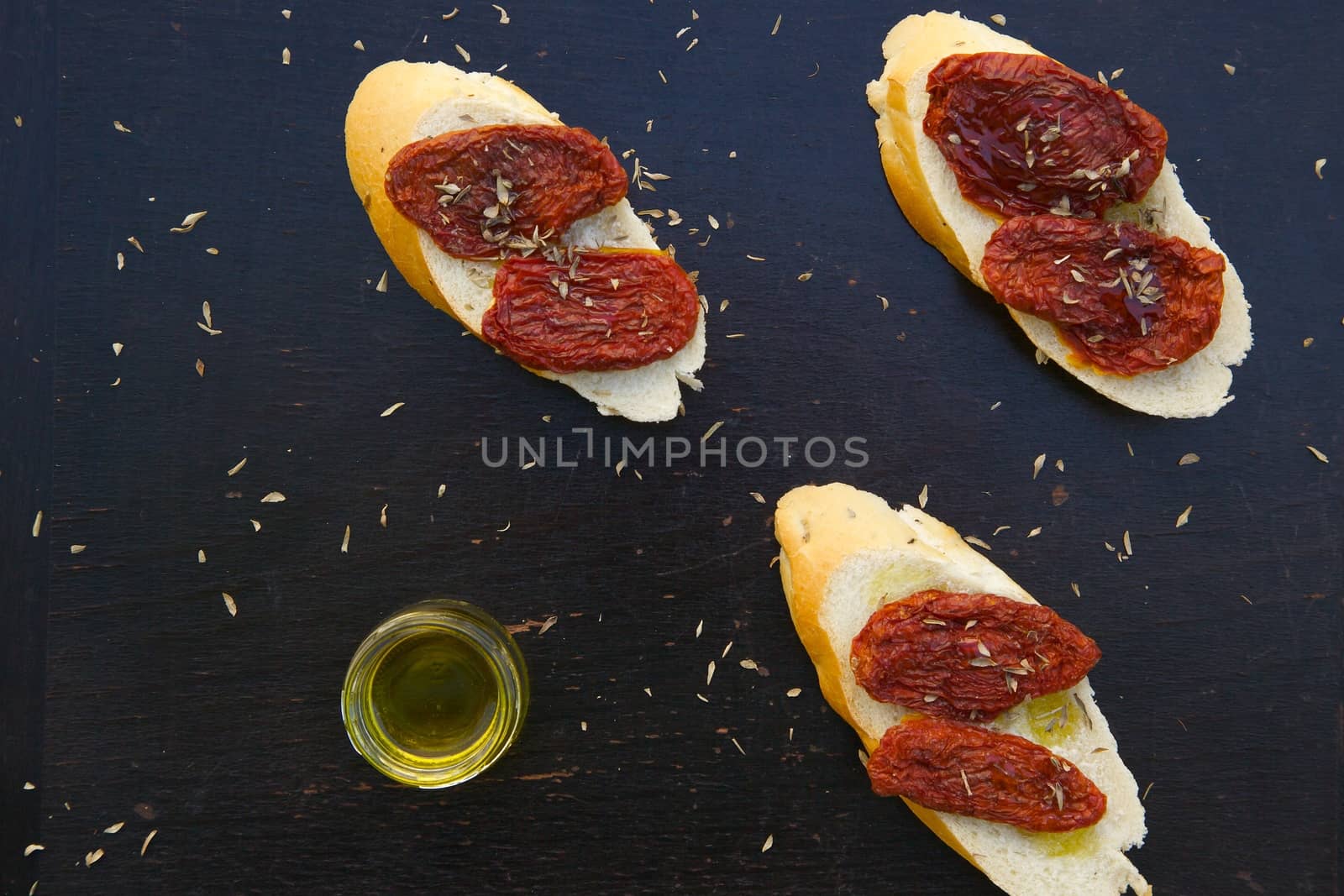 Flavorful starter - sun-dried red tomatoes on the pieces of French baguette by tolikoff_photography