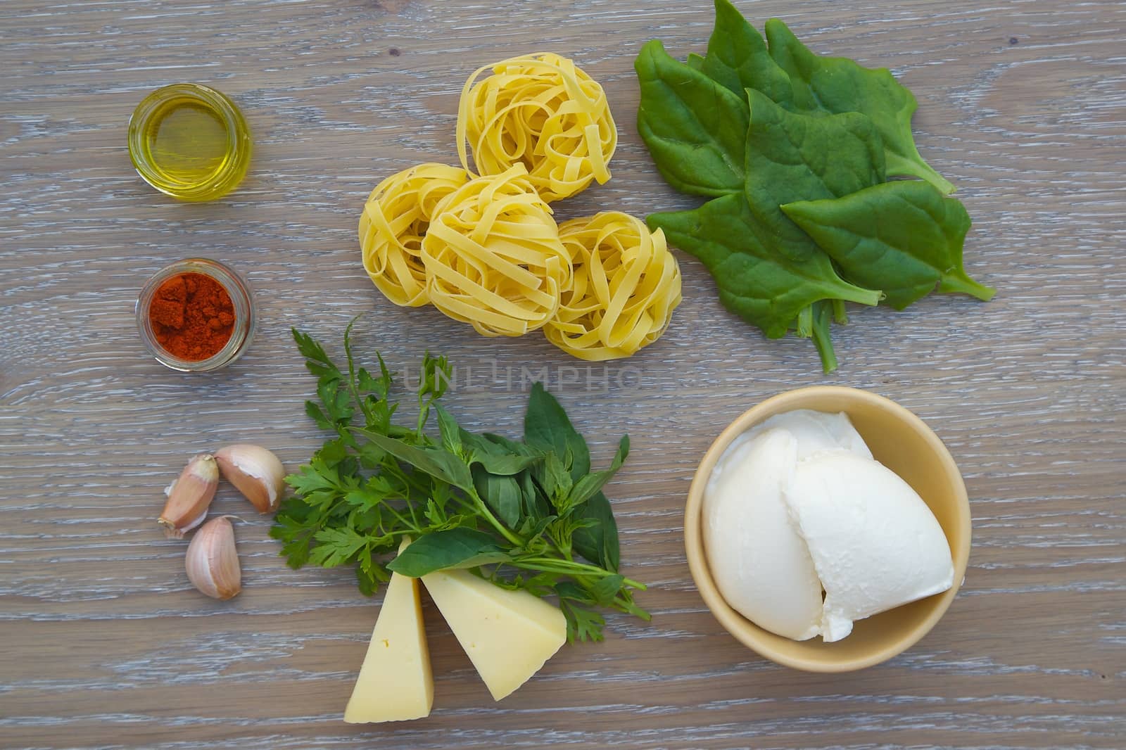 Food ingredients for preparing pasta with ricotta and spinach on the wooden surface
