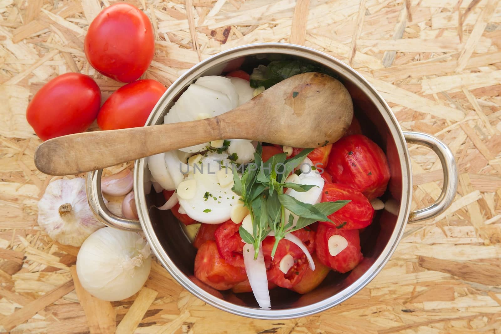 Prepared food ingredients for cooking Italian tomato sauce - salsa. Ingredients are placed in the pot which is on the wooden surface