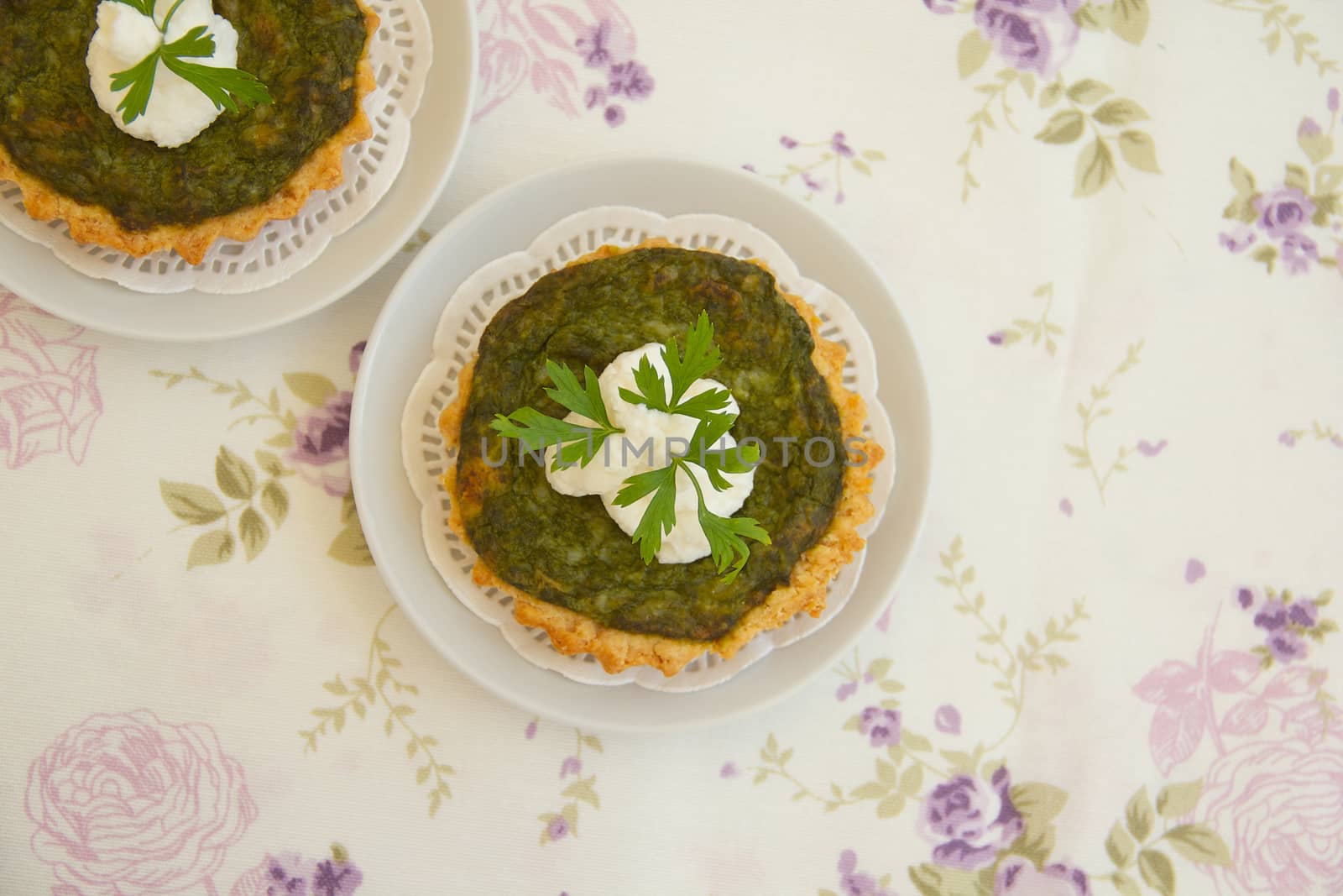 Homemade mini spinach and ricotta tarts on a white decorative na by tolikoff_photography