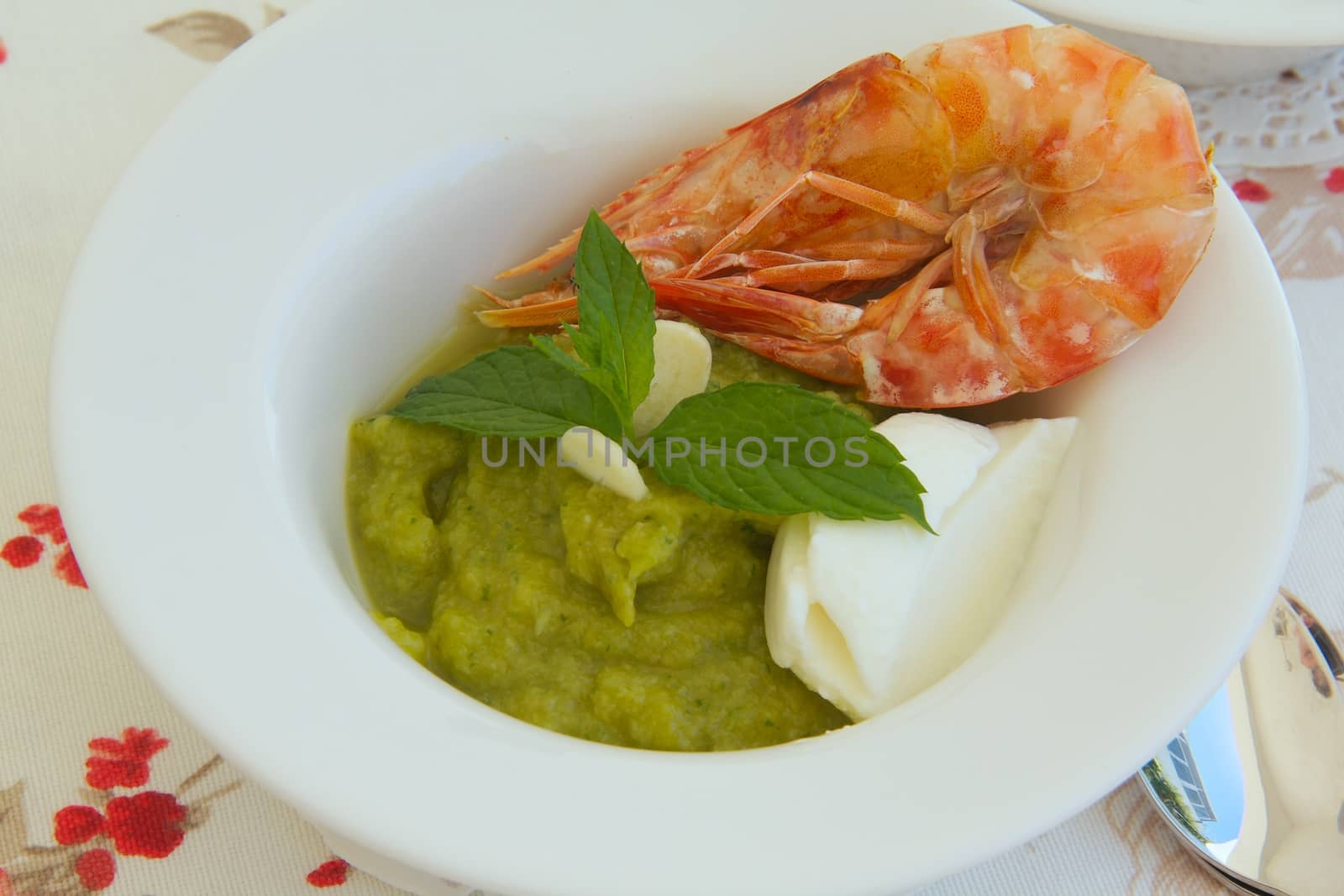 Zucchini cappuccino soup with yogurt,shrimps and fresh peppermint leaves.Close up